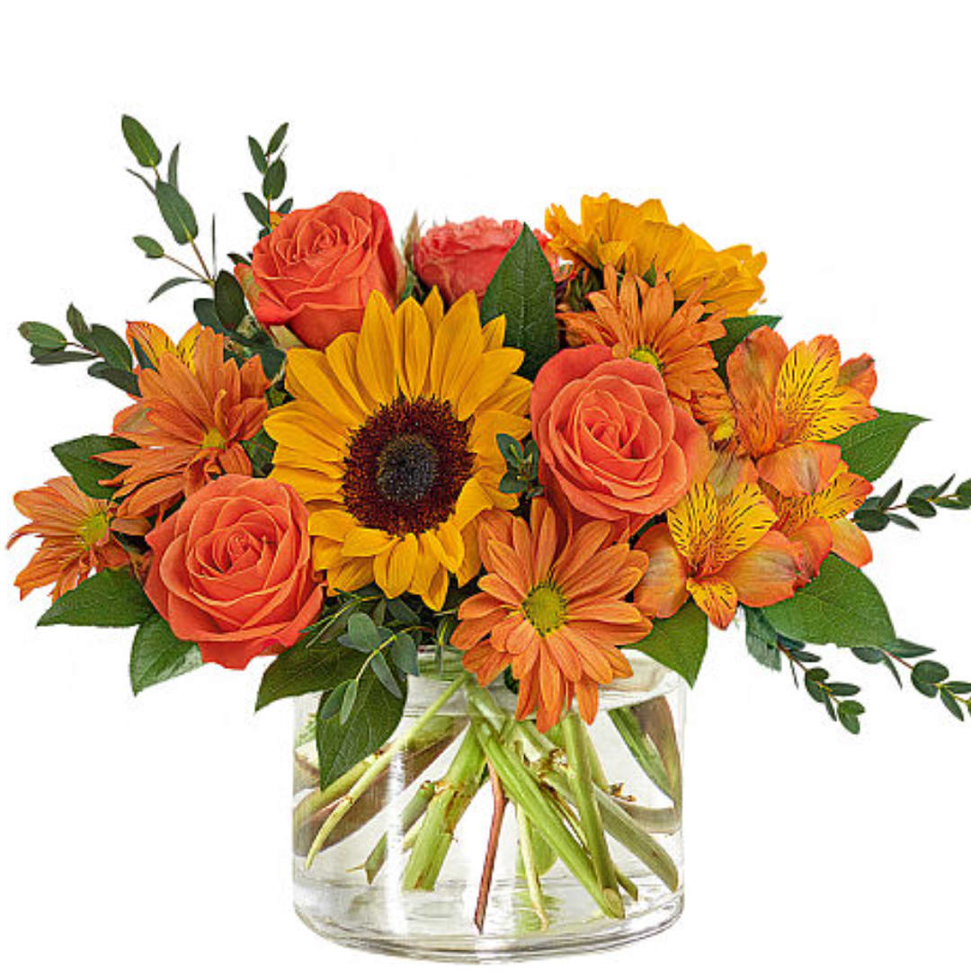 Orange roses and sunflowers in a clear glass vase
