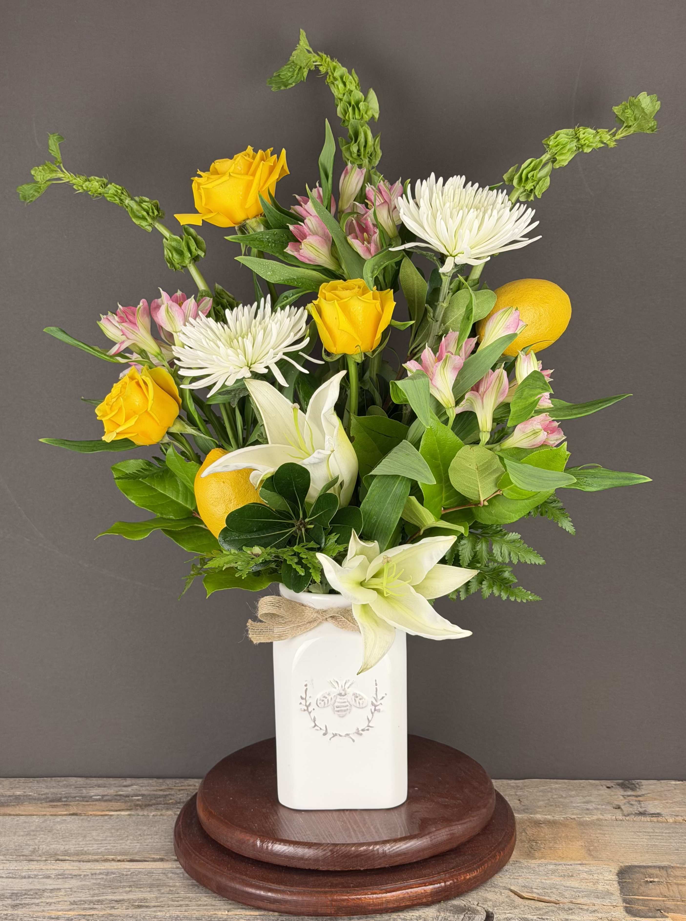 Bouquet of yellow roses, white lilies, and white chrysanthemums in a white vase