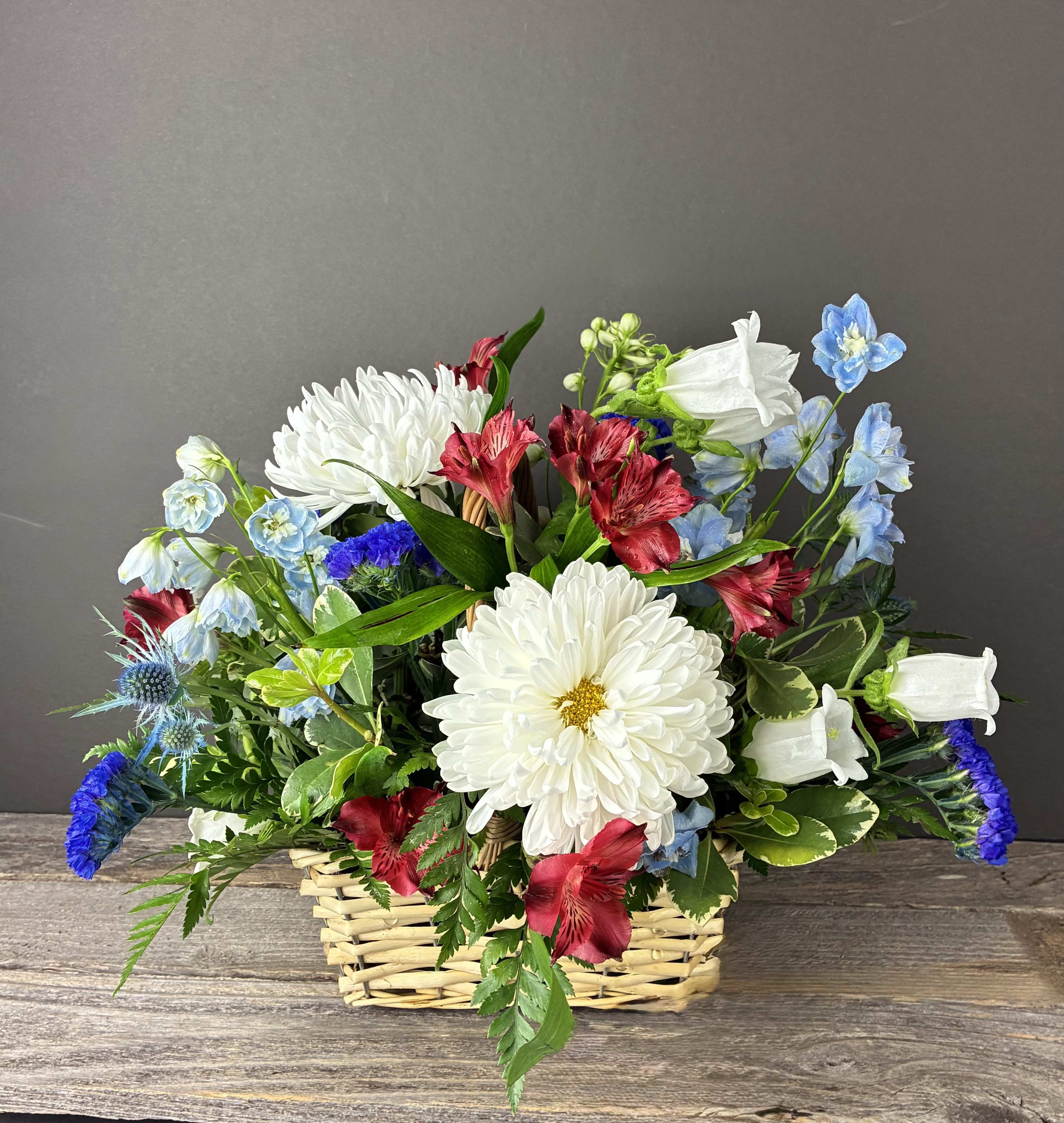 Red White and Bloom - Red, white, and blue flowers arranged in a handheld basket. Perfect for celebrating holidays, or for honoring the life of a loved one.