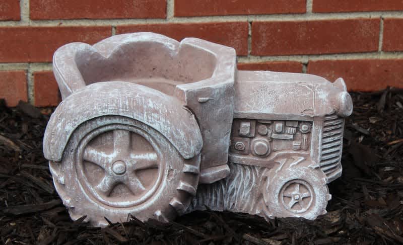 Decorative tractor-shaped planter in a garden bed