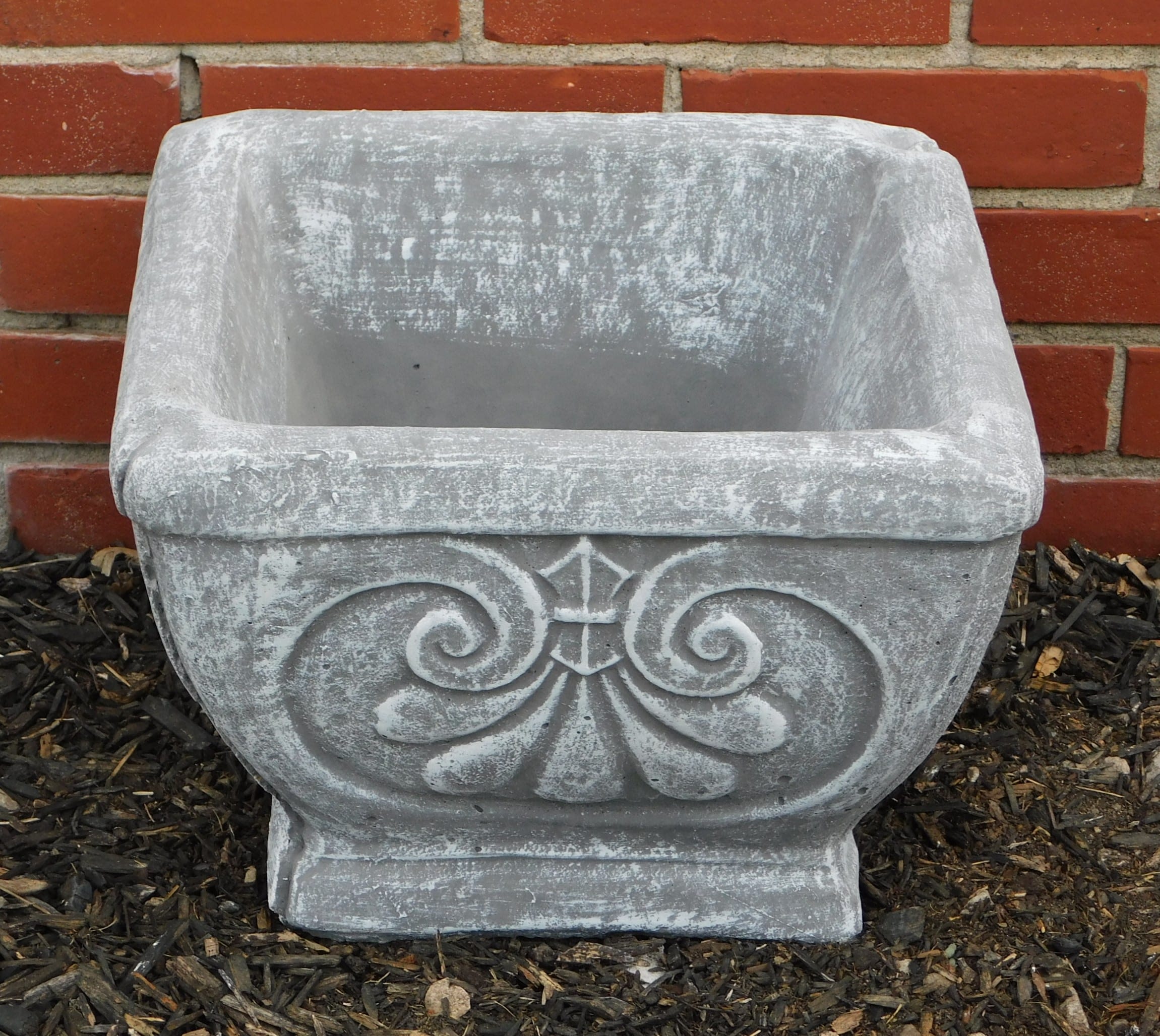 Empty gray stone planter with decorative scrollwork