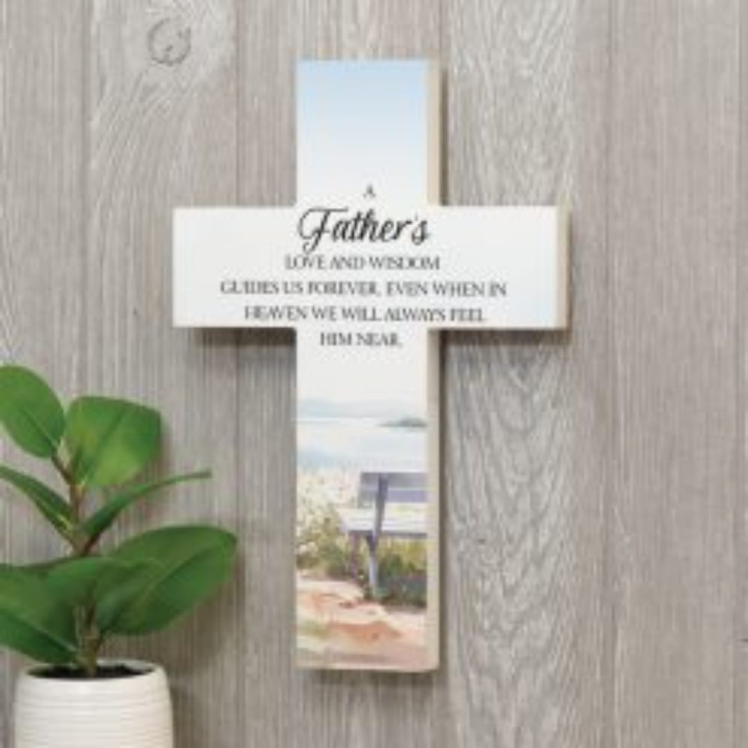 Cross-shaped memorial plaque with a Father’s tribute and a potted plant beside it