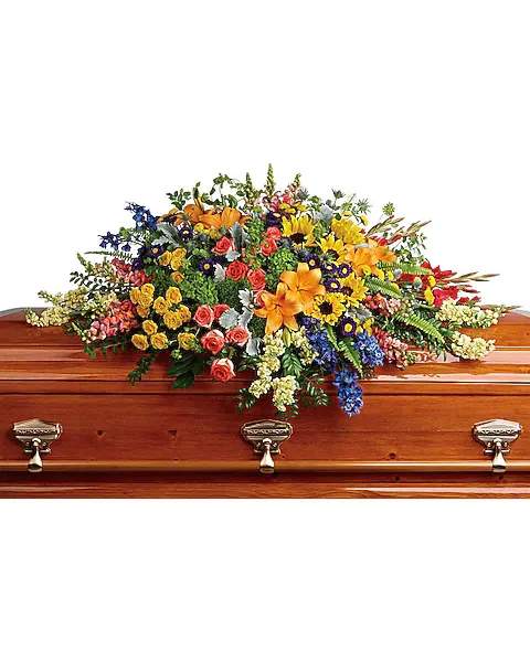 Colorful Reflections Casket Spray - "Full of light and love, this colorful casket spray celebrates a bright life with the natural beauty of hydrangea, roses, lilies and sunflowers. Green hydrangea, orange roses, yellow spray roses, orange asiatic lilies, red gladioli, large yellow sunflowers, blue delphinium, orange snapdragons, light yellow stock, purple matsumoto asters, and yellow button spray chrysanthemums are accented with green trick dianthus, blue eryngium, bupleurum, dusty miller, huckleberry, sword fern, lemon leaf."