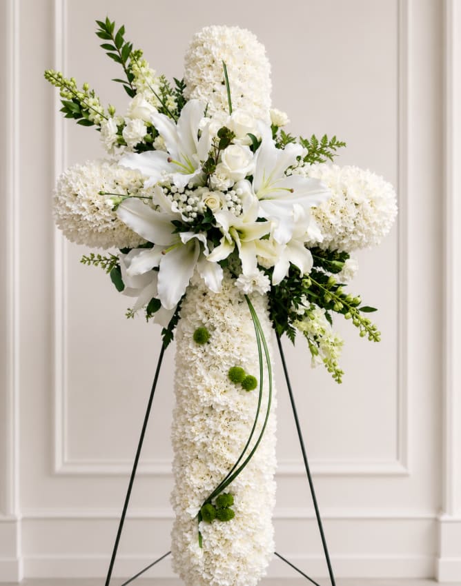 White floral standing cross with lilies and roses on an easel