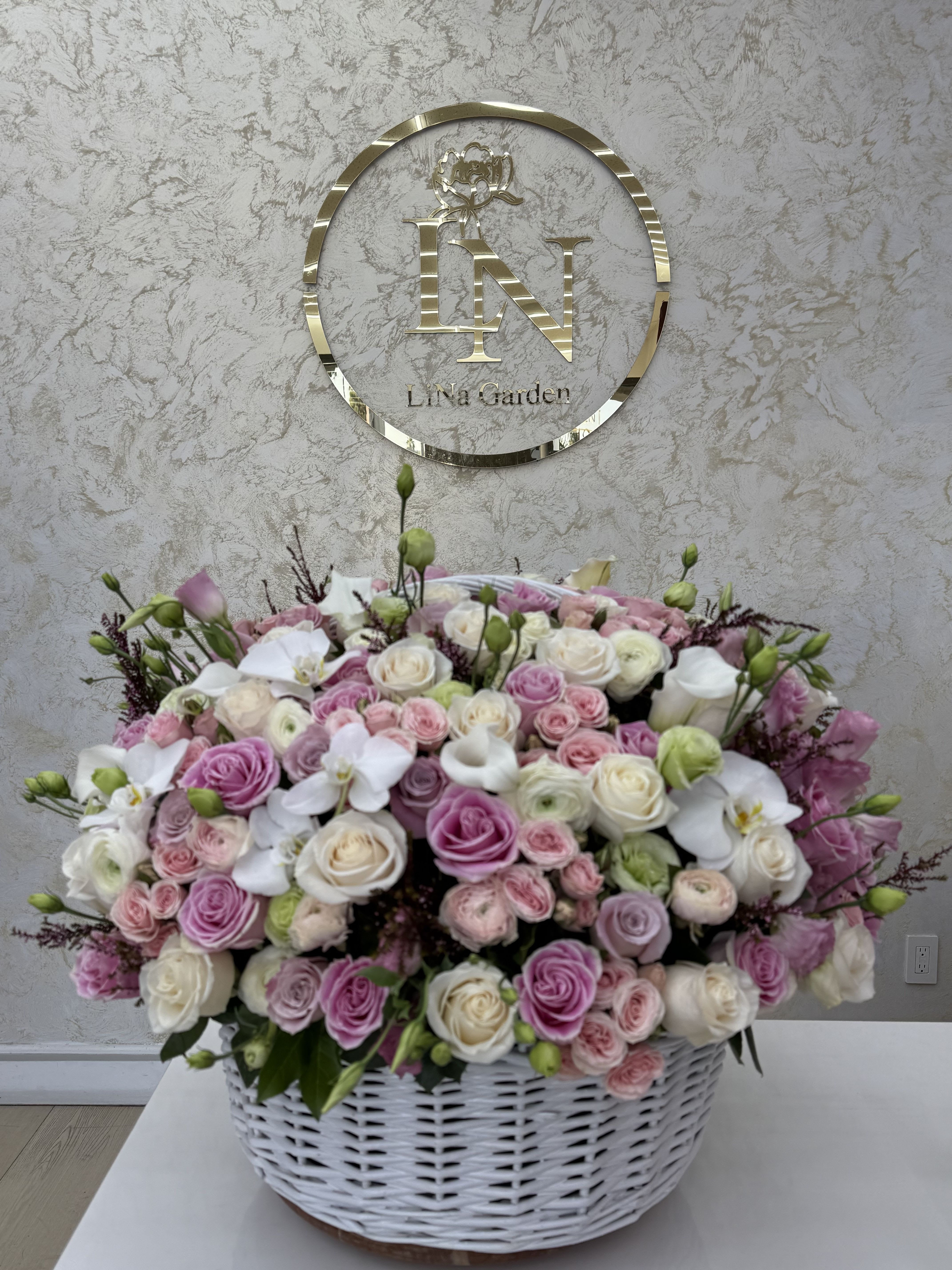 Large basket arrangement of pink and white roses with white orchids