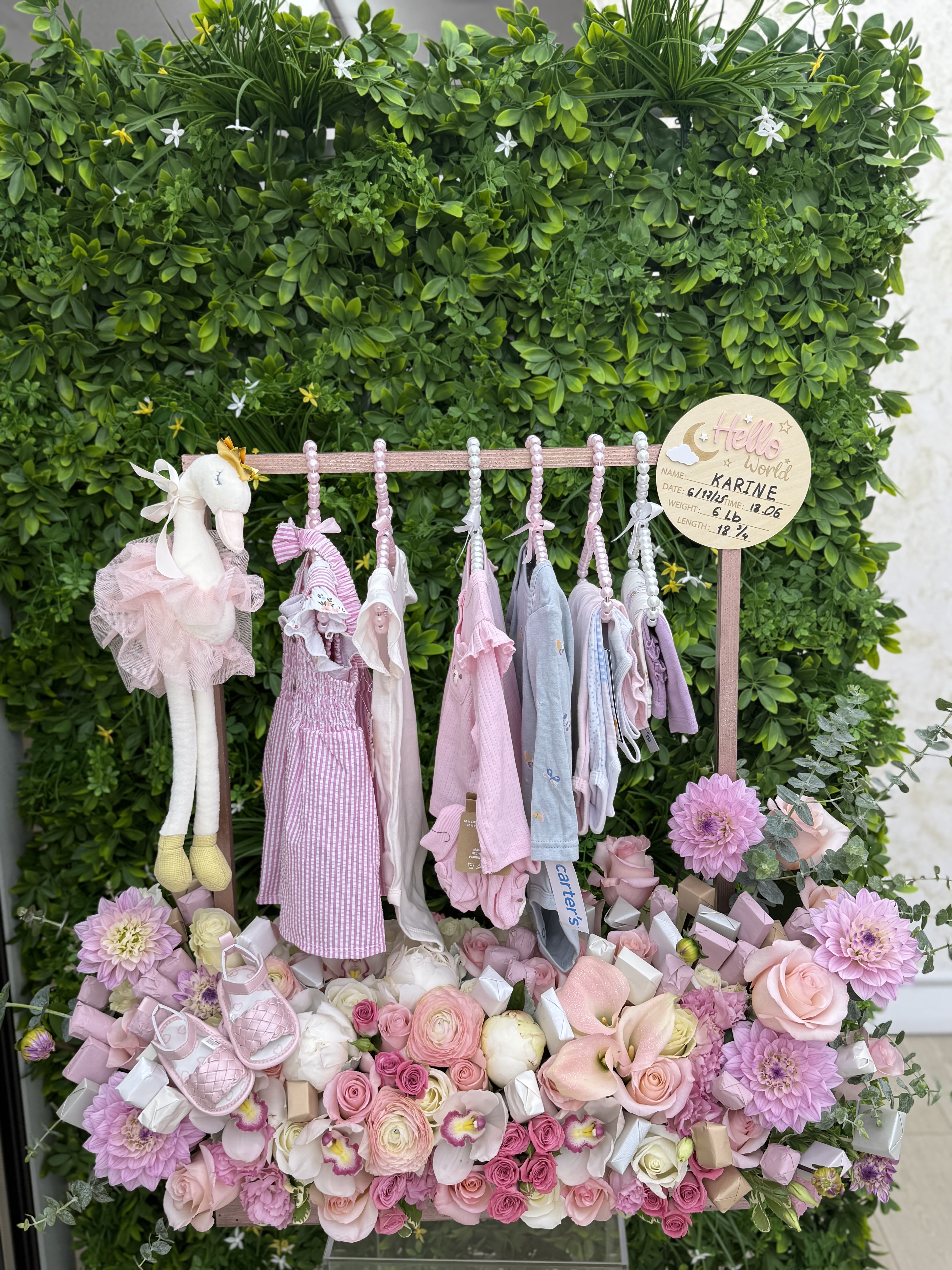 Pink baby gift display with flowers, clothes, and a plush bunny