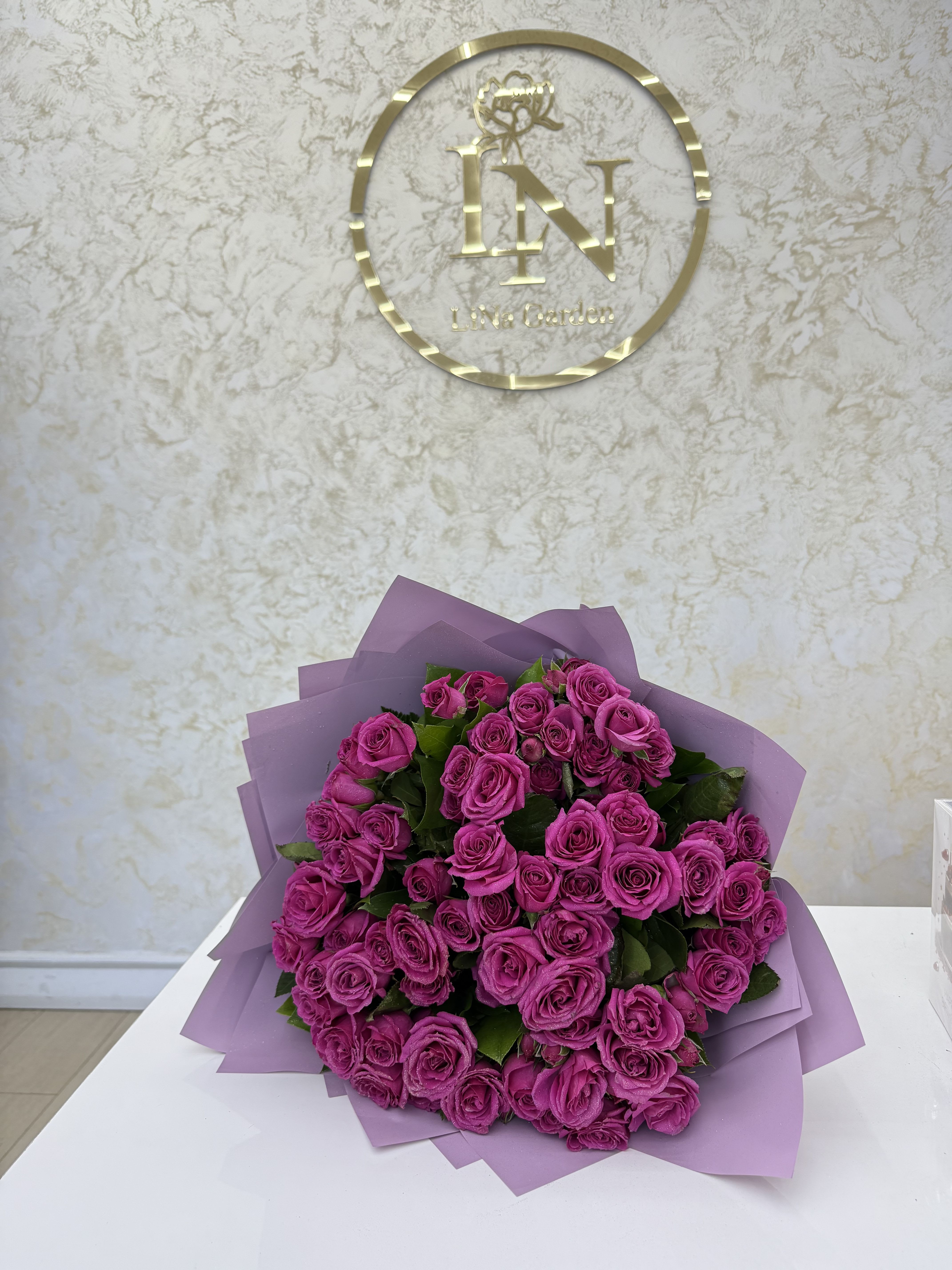 Bouquet of bright pink roses wrapped in lavender paper