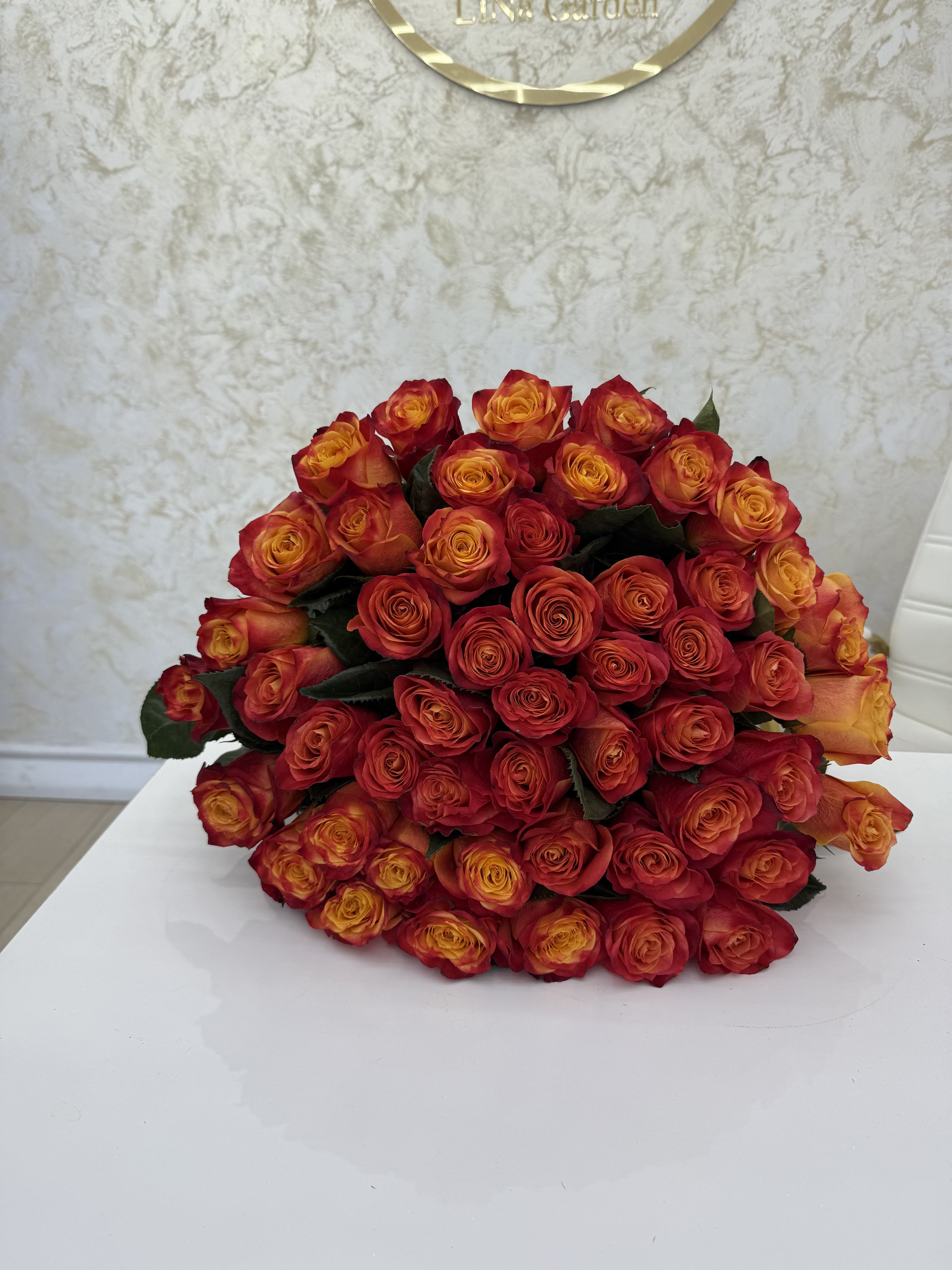 Large bouquet of red and orange roses on a white surface