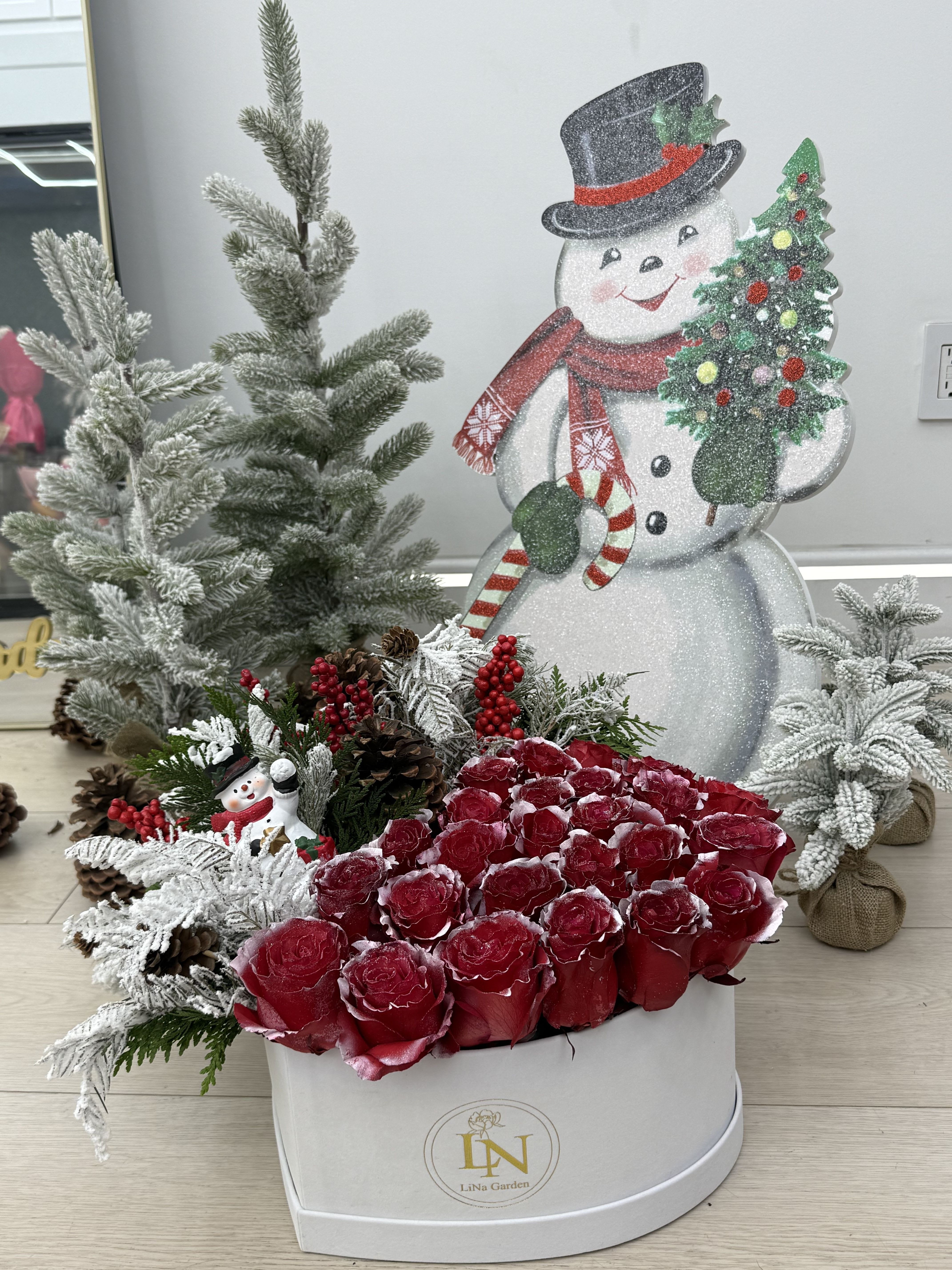 Red roses in a white hatbox with Christmas decorations