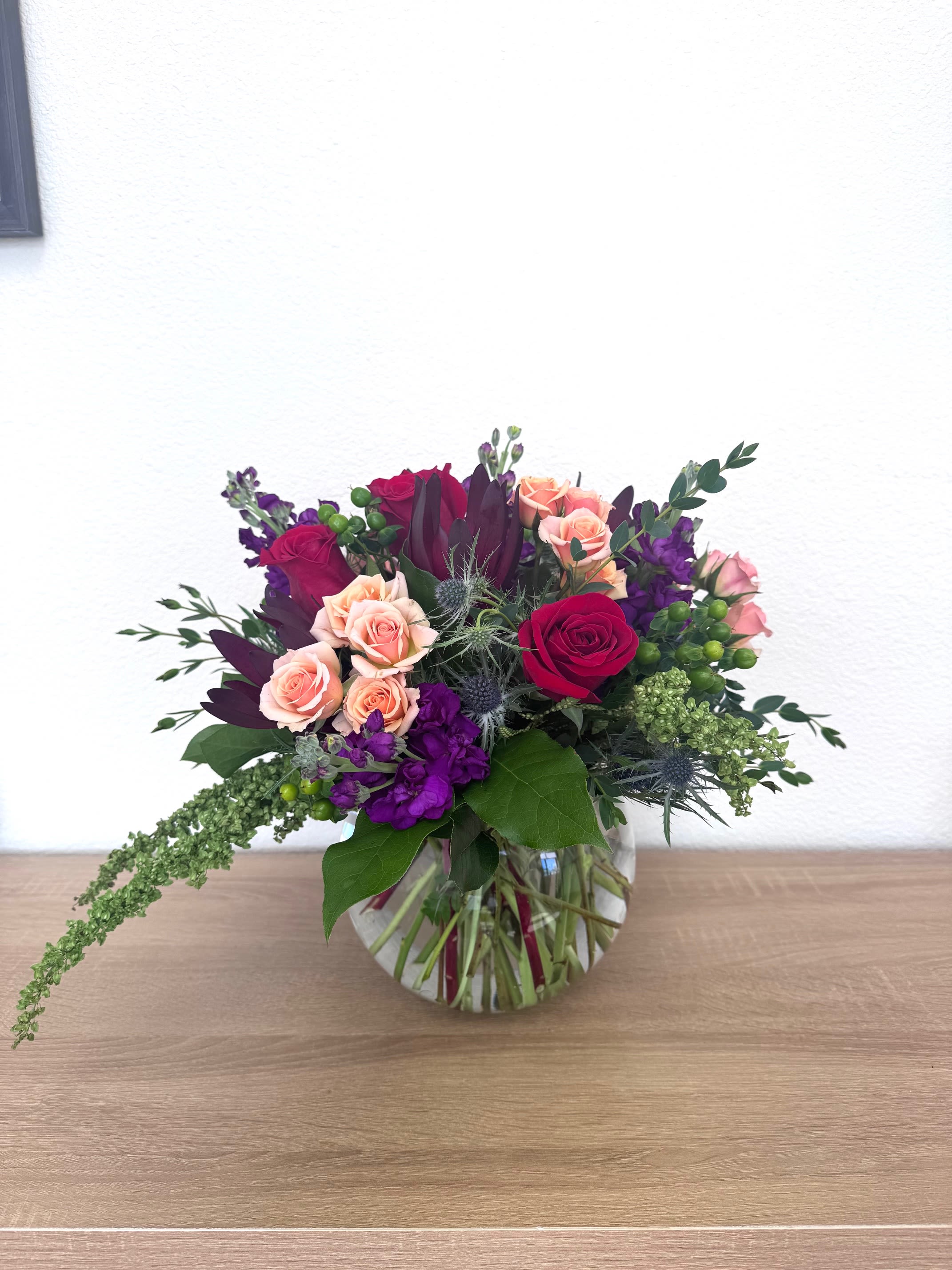 Mixed bouquet of pink and purple roses in a clear glass vase