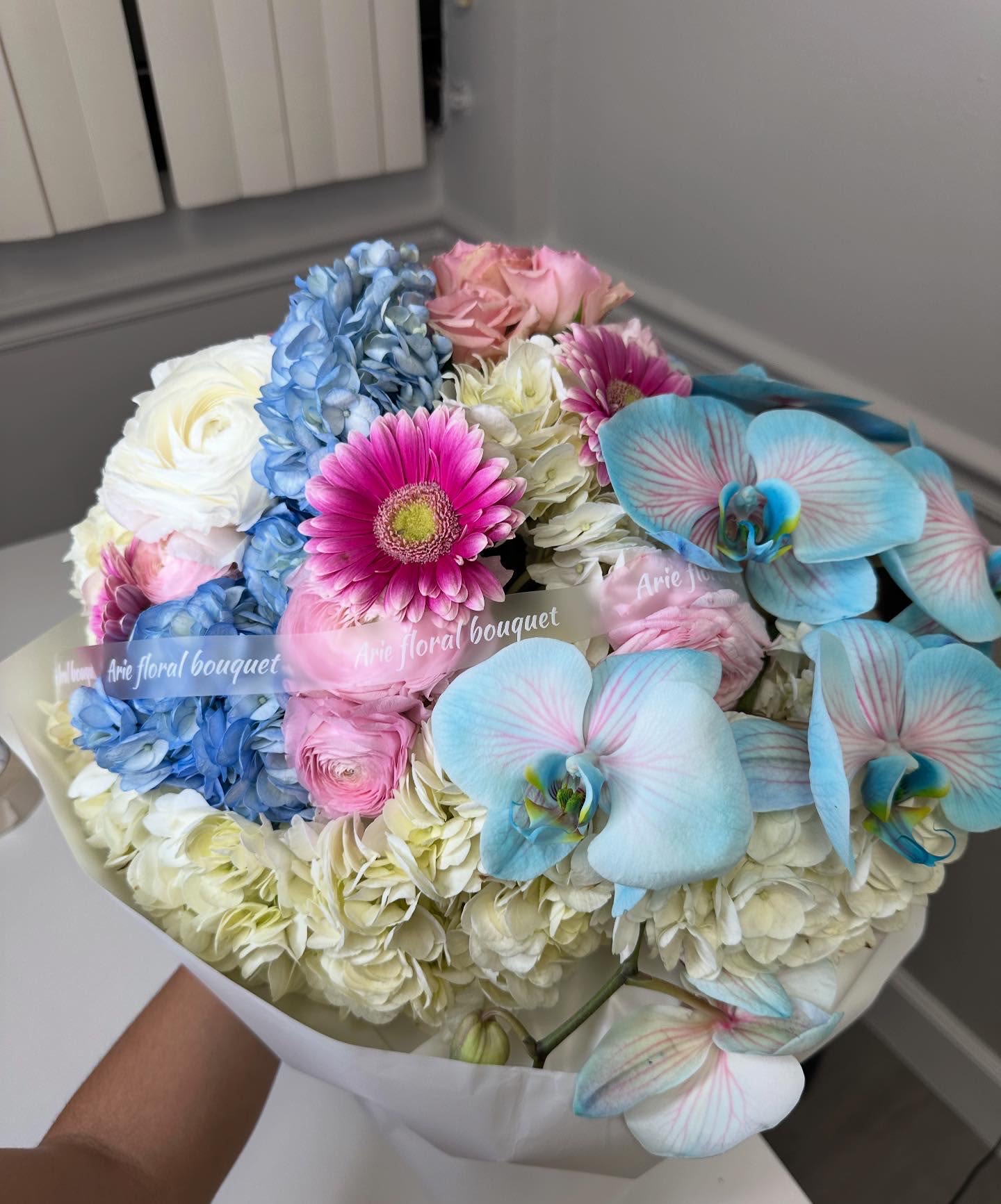 Bouquet of pastel flowers with blue orchids and pink daisies