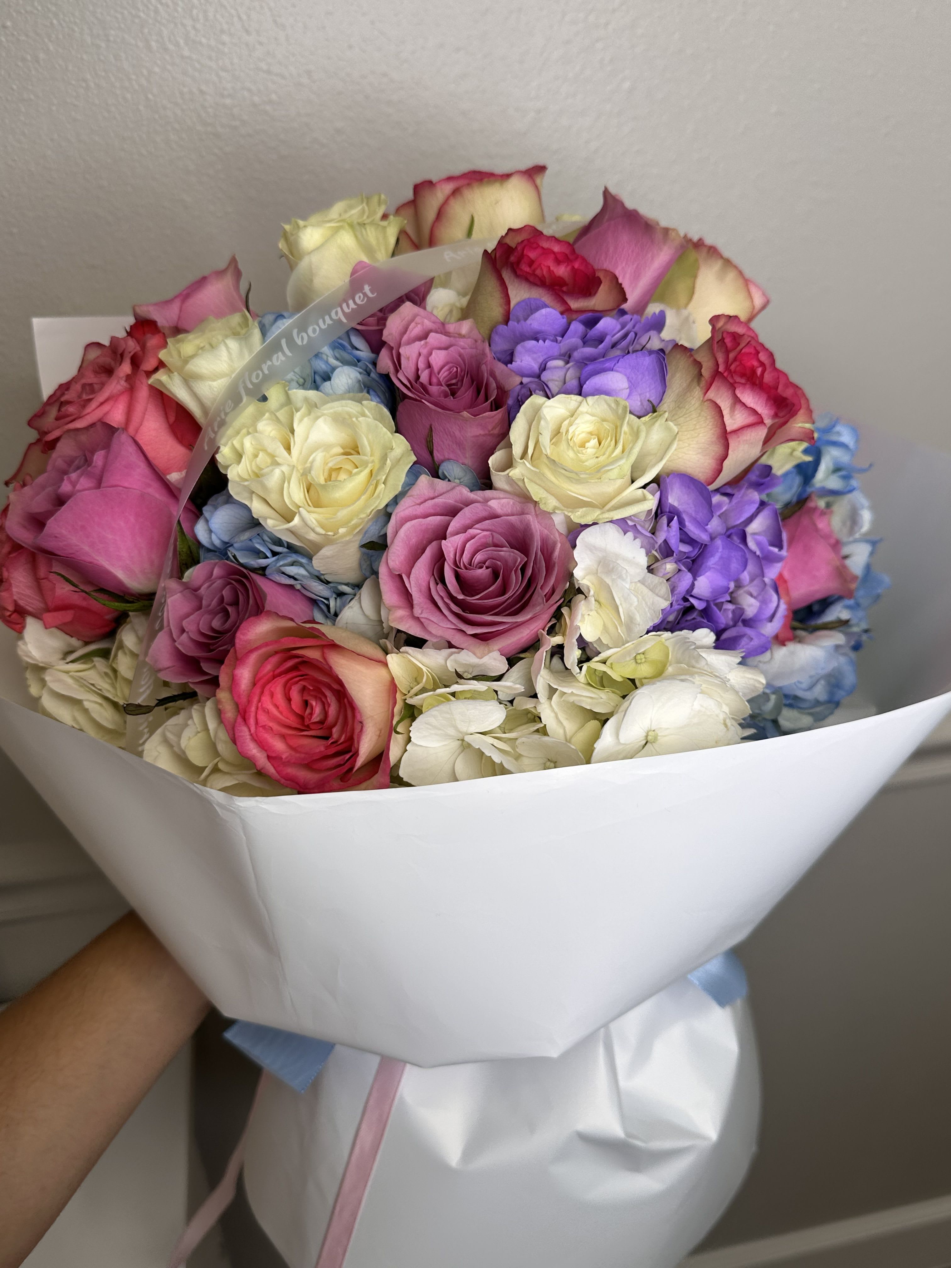 Bouquet of multicolored roses wrapped in white paper