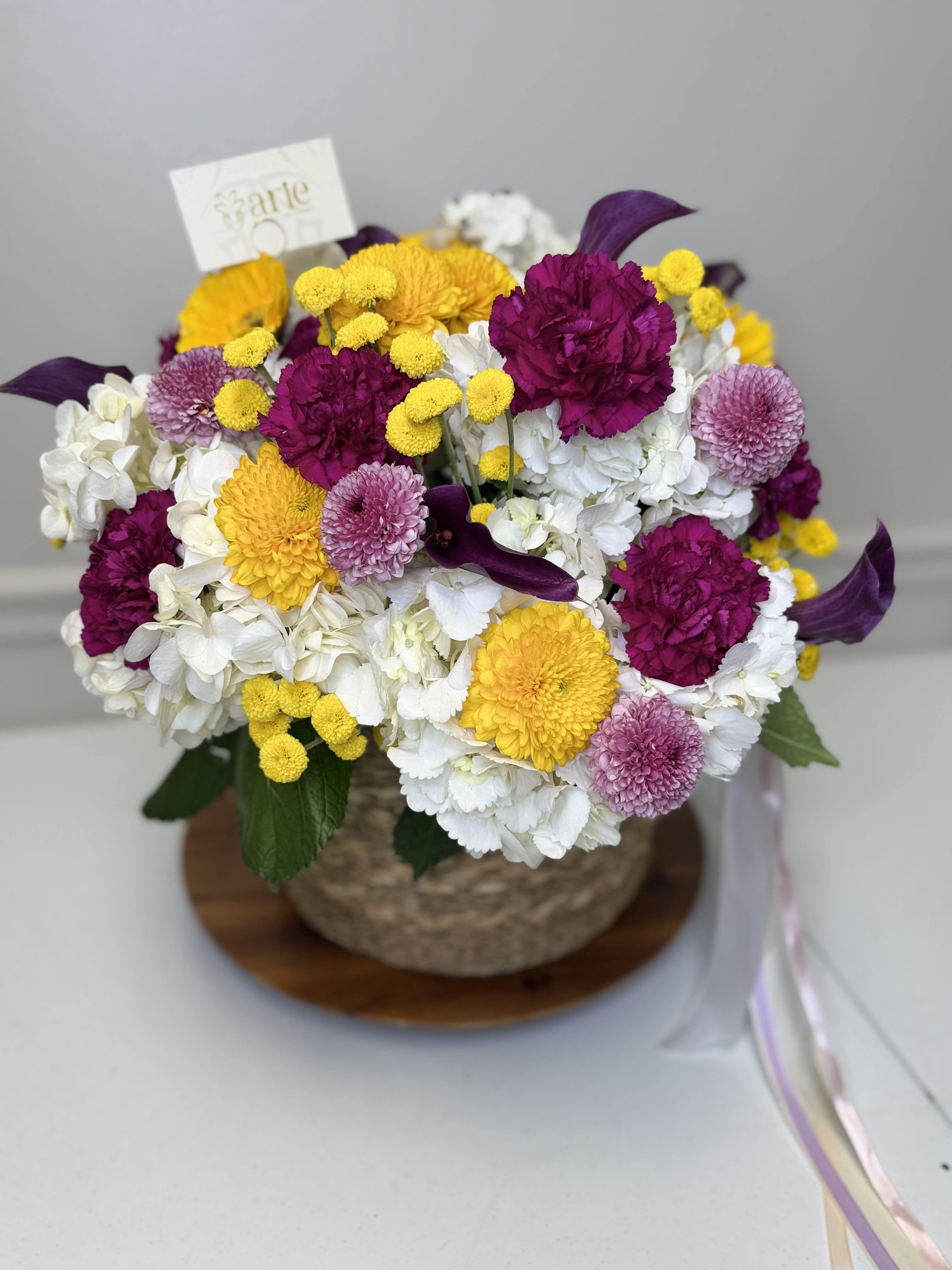 Mixed bouquet of white, yellow, magenta, and lavender flowers in a basket