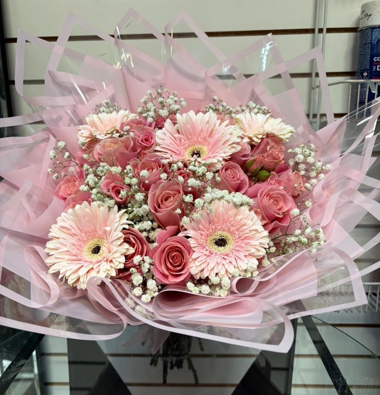 Pink bouquet with roses, gerbera daisies, and baby's breath wrapped in pink paper