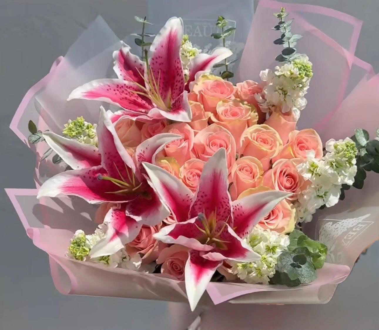 Bouquet of pink roses and pink lilies wrapped in pale pink paper