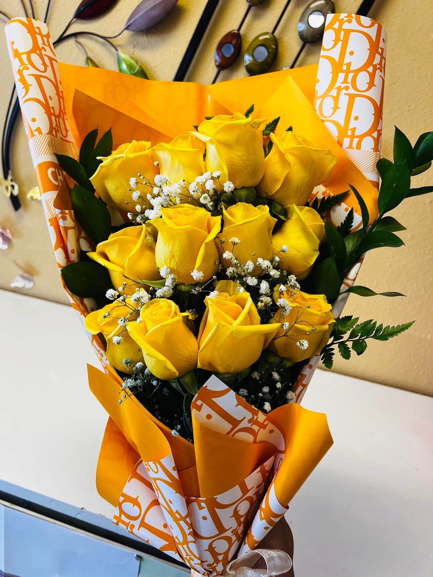 Bouquet of yellow roses with white filler flowers in orange wrapping