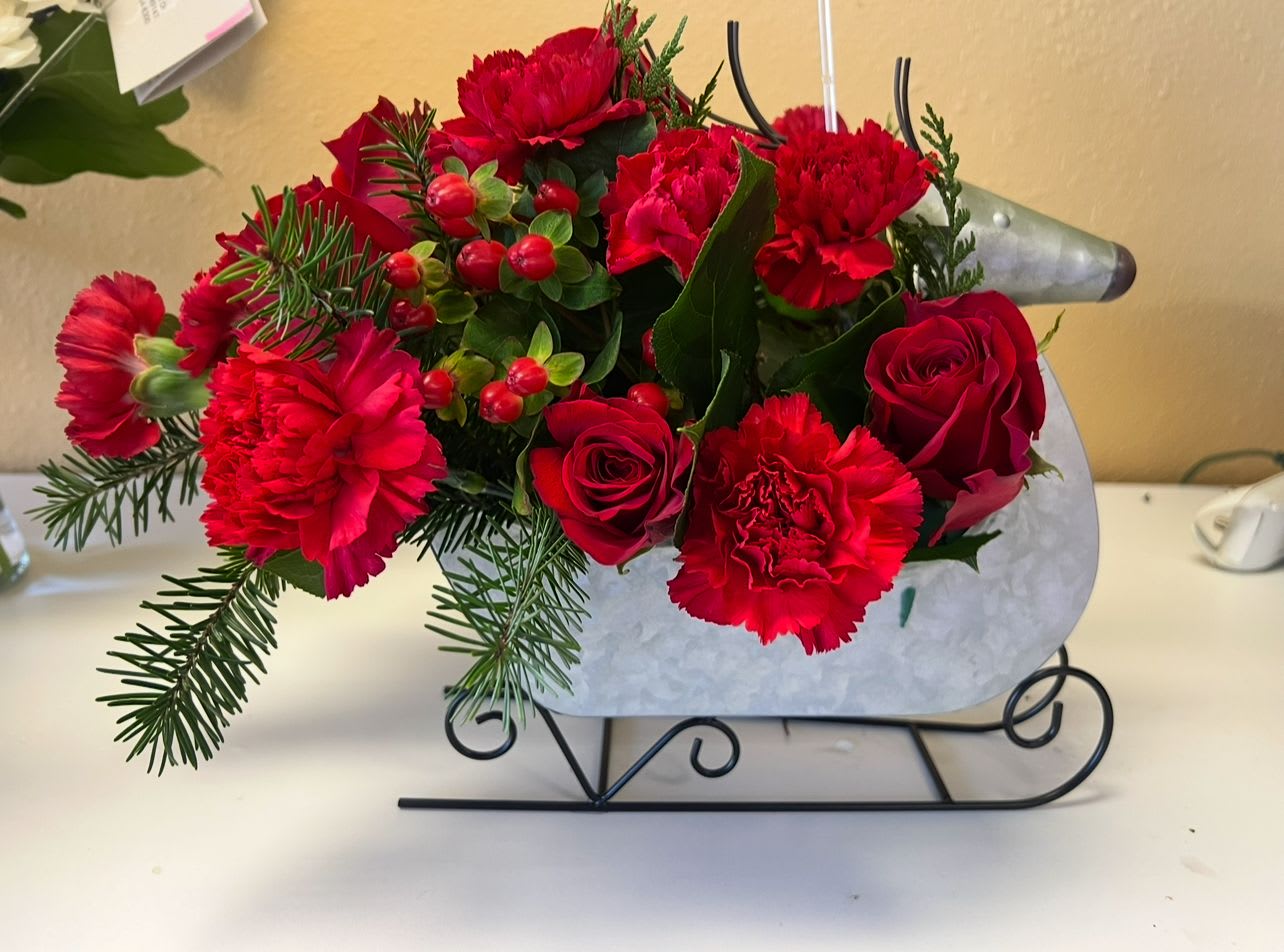 Red carnations and roses arranged in a sleigh-shaped container