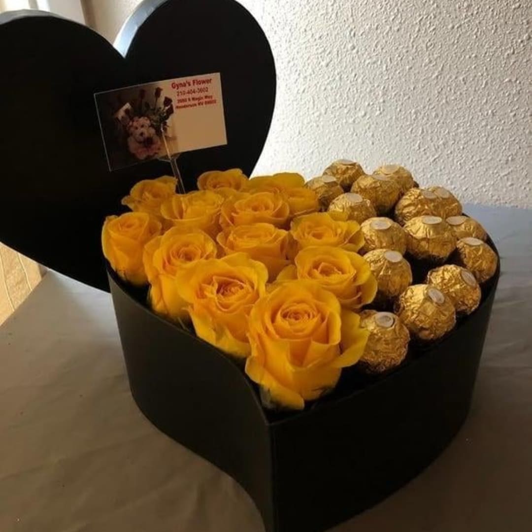 Yellow roses and gold-wrapped chocolates in a black heart box