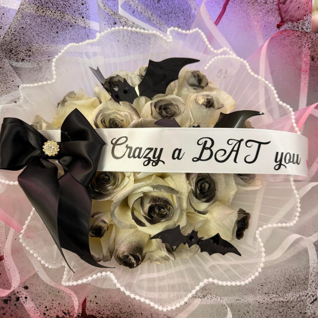 Bouquet of pale roses with black bat decorations and a ribbon banner