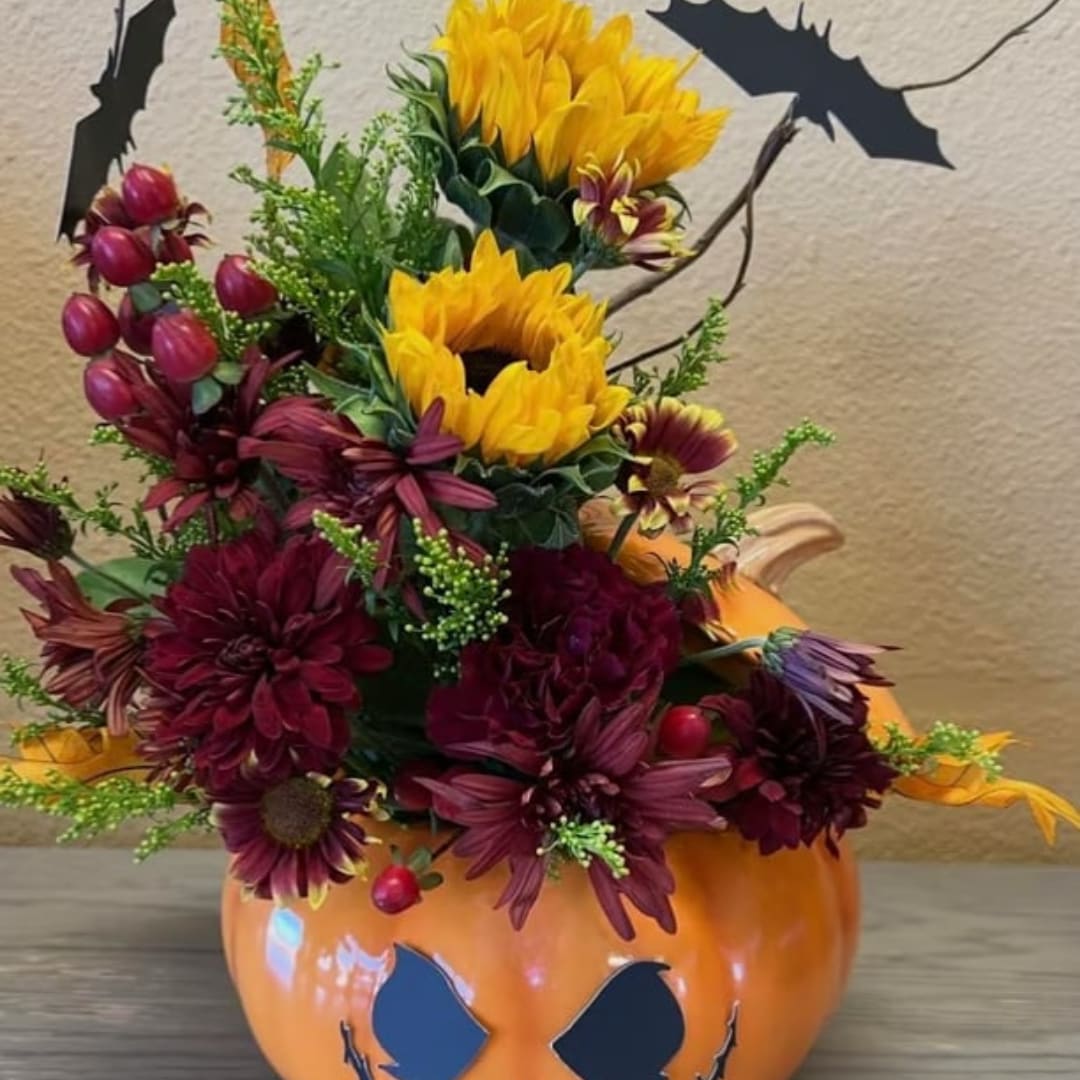 Sunflower and burgundy chrysanthemum arrangement in a pumpkin container