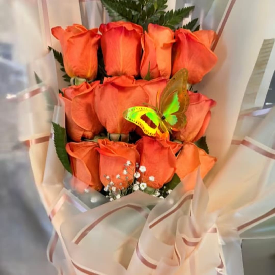 Bouquet of orange roses wrapped in pale peach paper with a butterfly accent