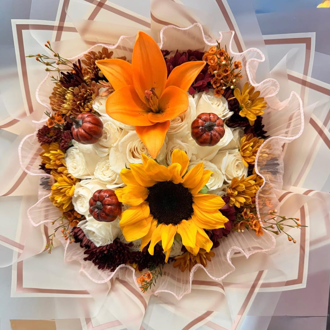 Bouquet of orange lilies and sunflowers with white roses and small pumpkins
