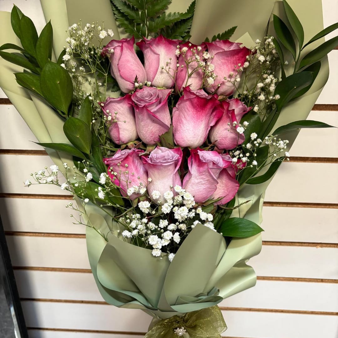 Bouquet of pink roses with baby's breath in green wrapping
