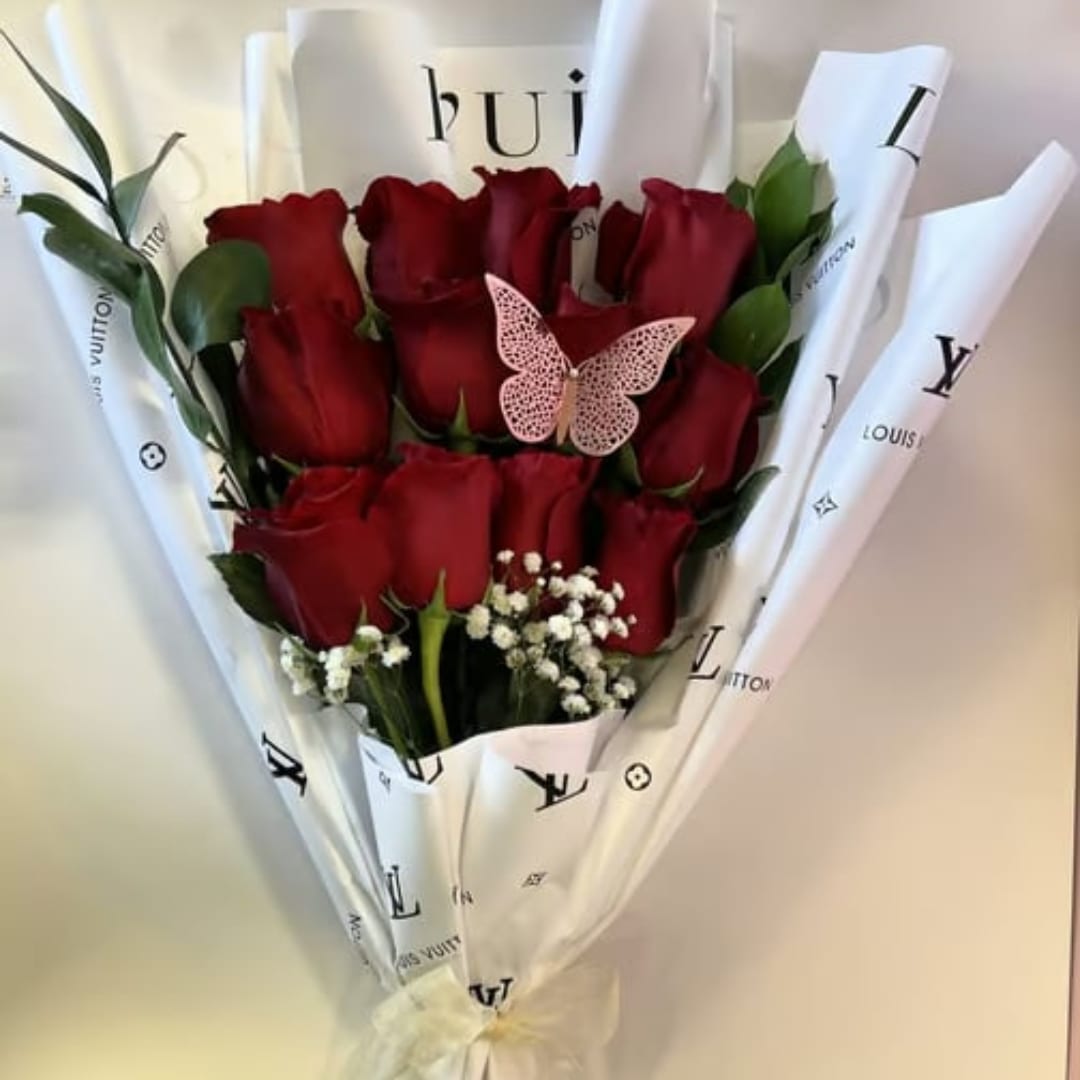 Bouquet of red roses wrapped in white branded paper with a butterfly accent