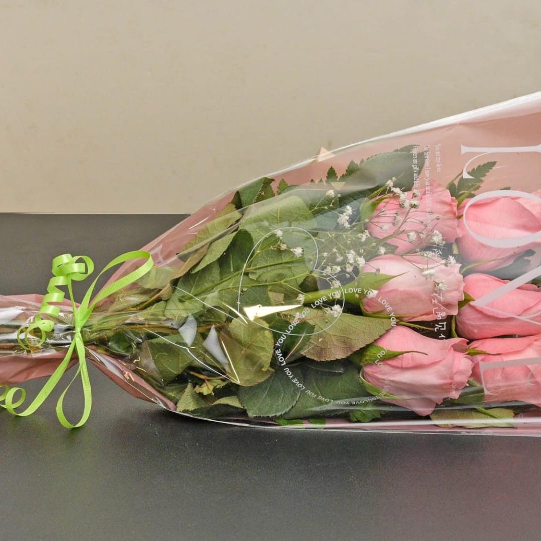 Wrapped bouquet of pink roses with baby's breath
