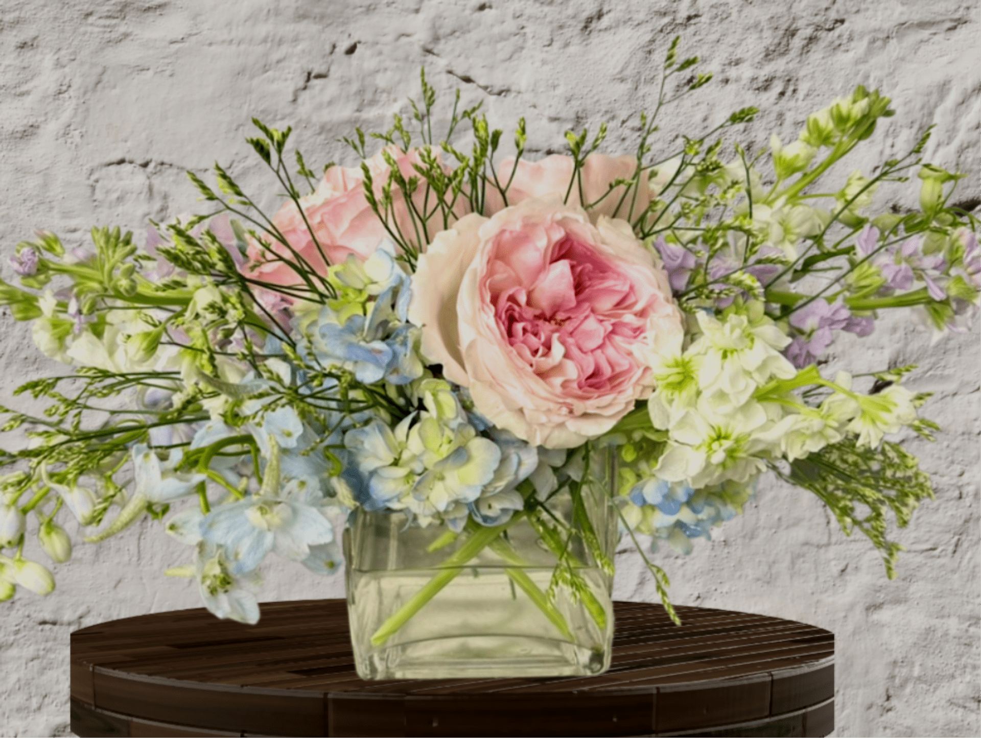Pastel bouquet of pink and blue flowers in a clear glass vase