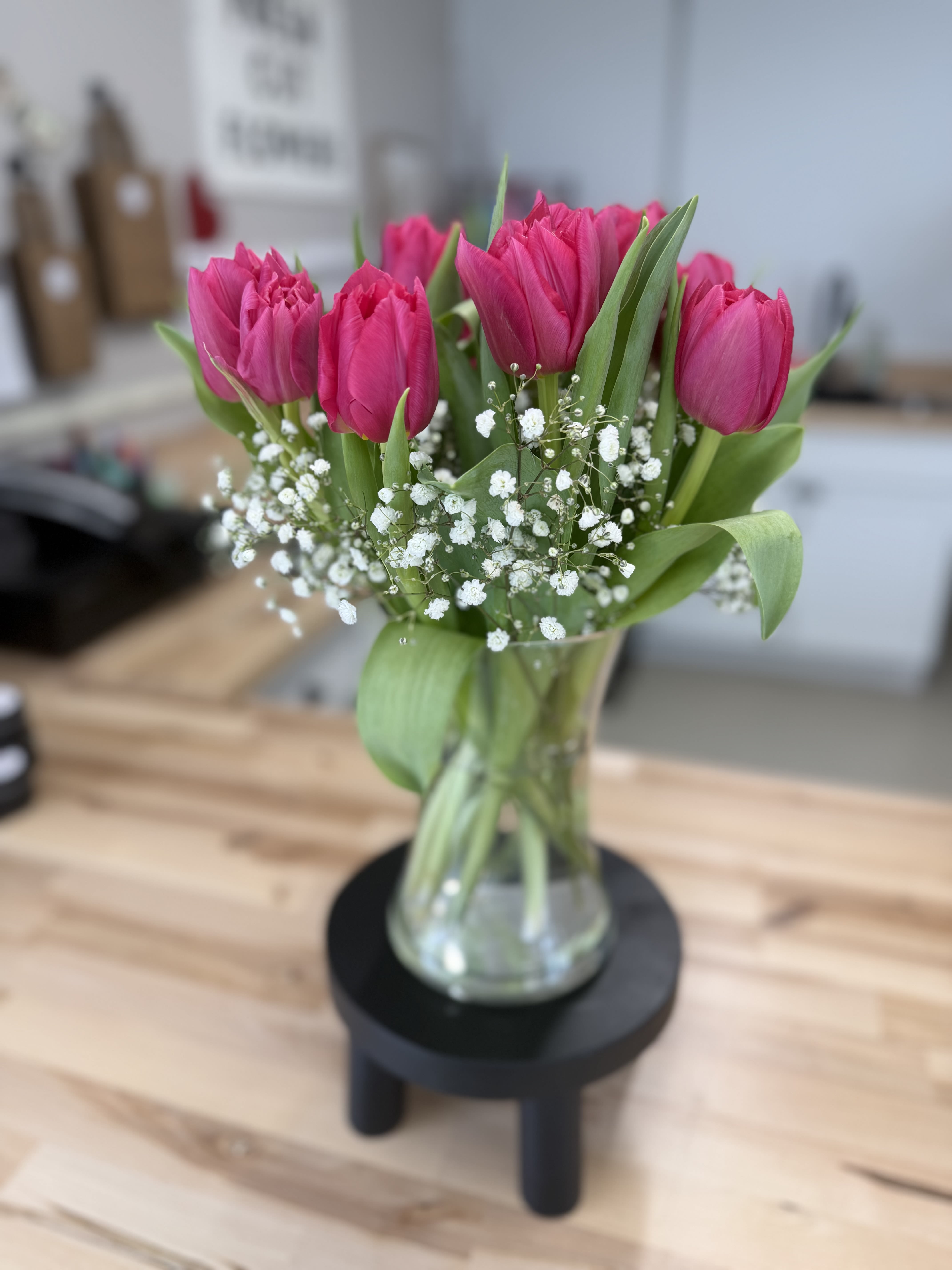 Pink tulips in a clear glass vase with white baby's breath