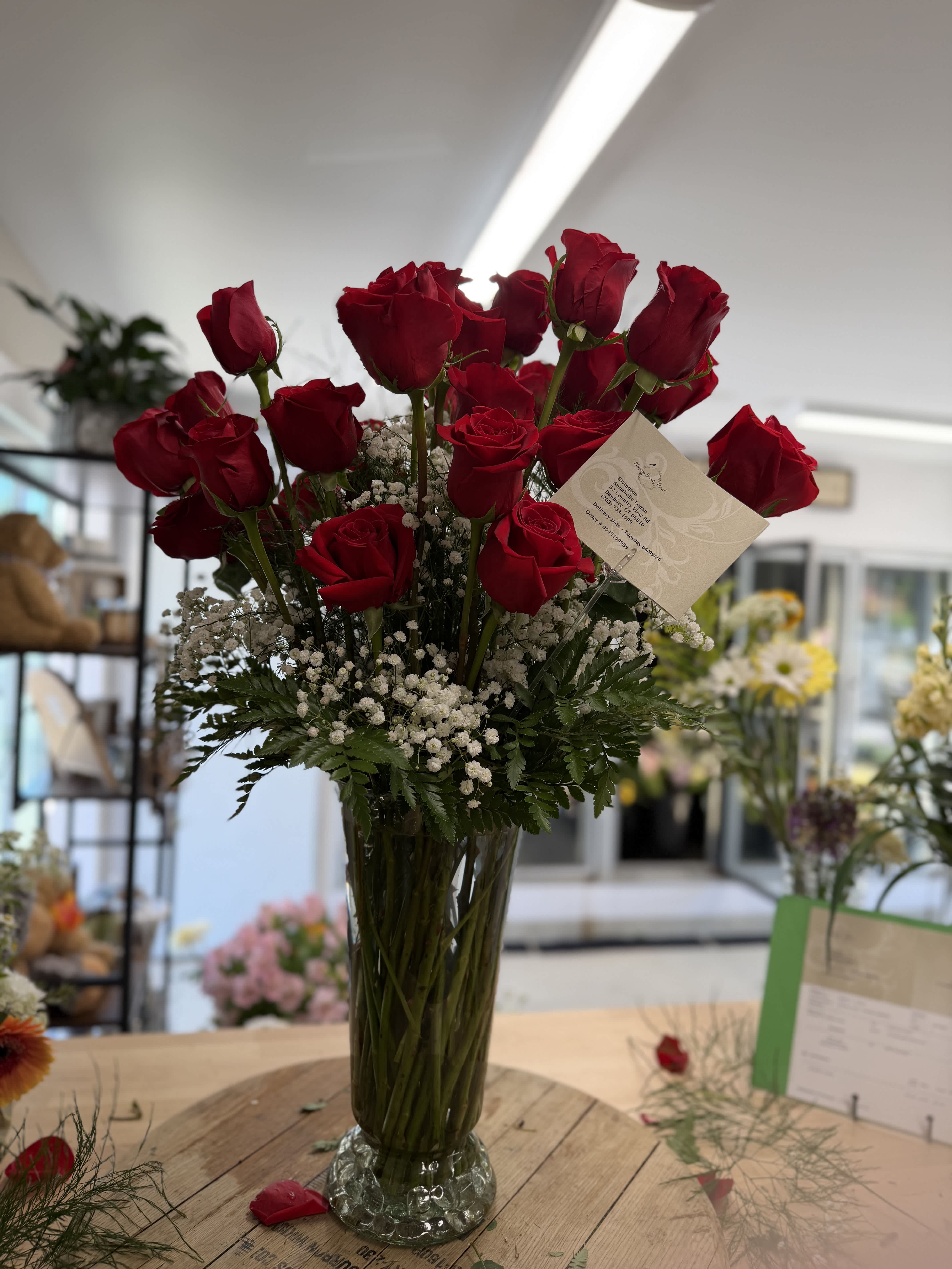 Tall vase arrangement of red roses with white baby's breath