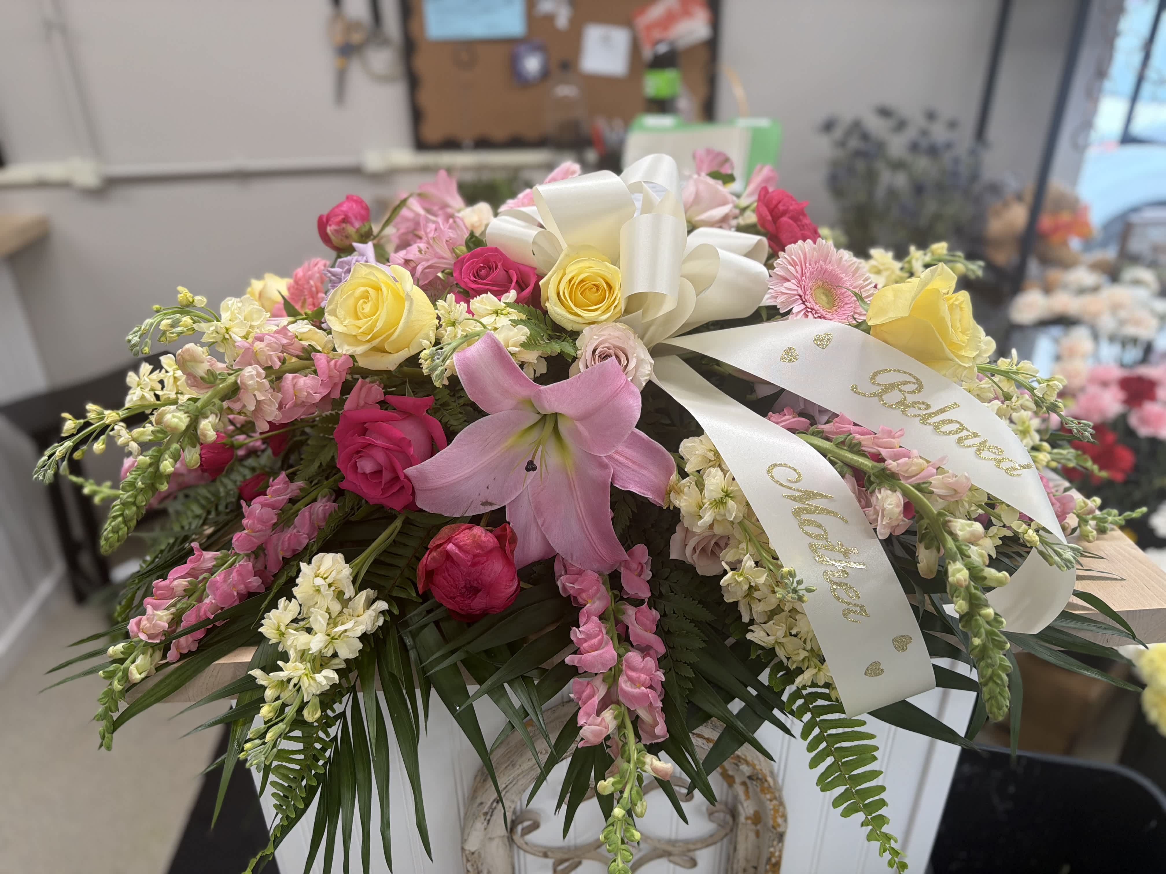 Pink and yellow rose arrangement with a pink lily and white ribbon