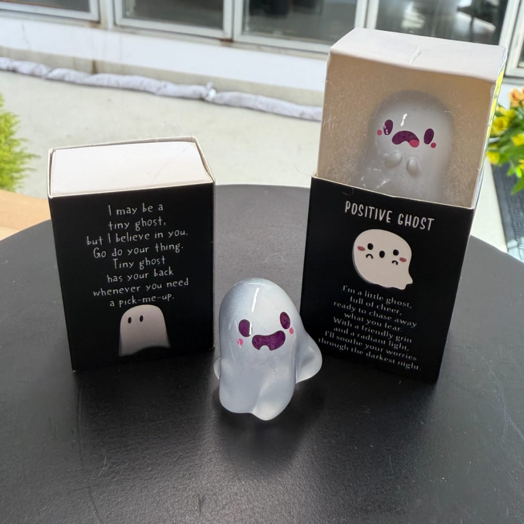 Small ghost figurines in black gift boxes on a table