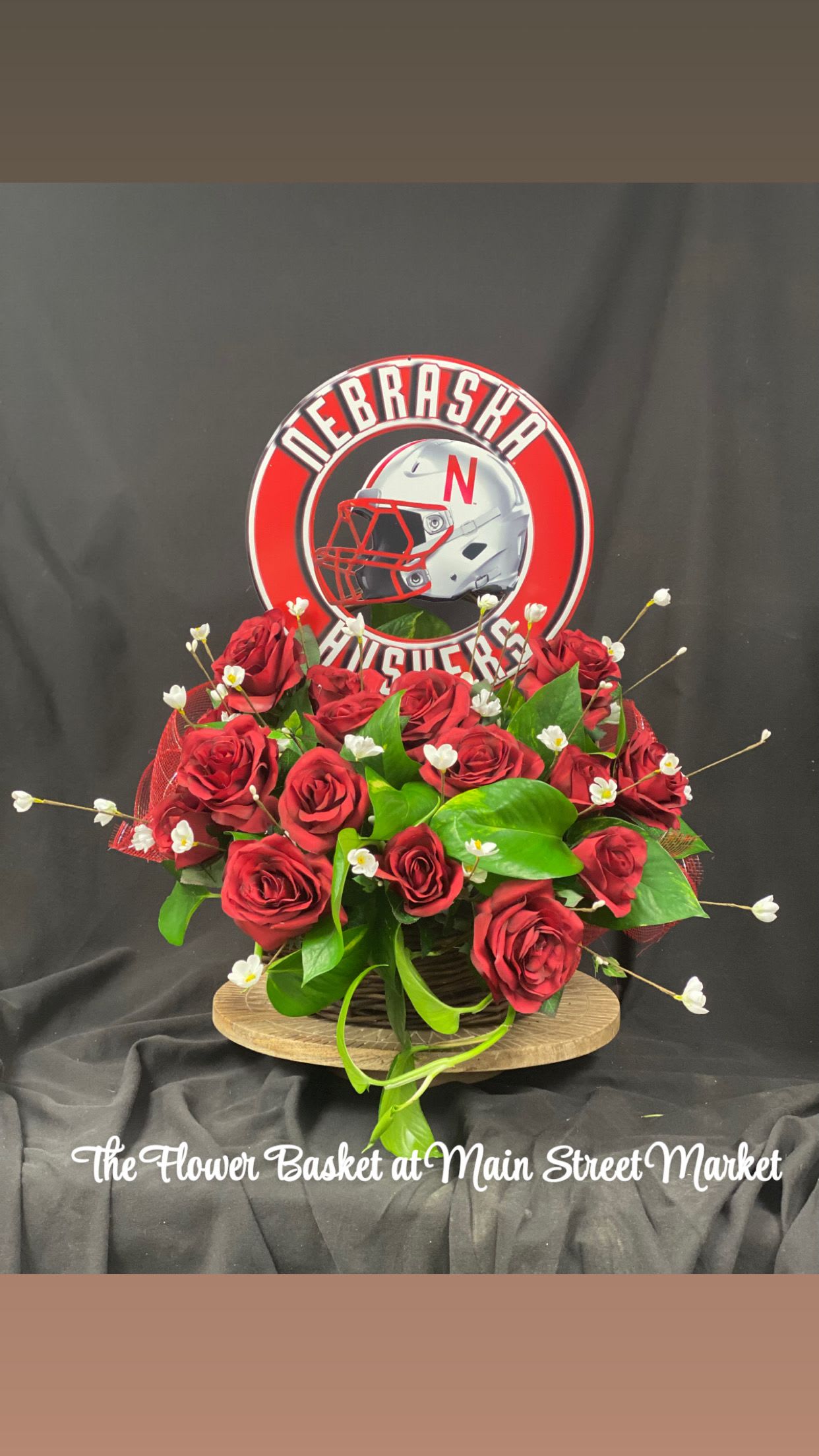 Red roses arranged with greenery and a Nebraska Huskers sign
