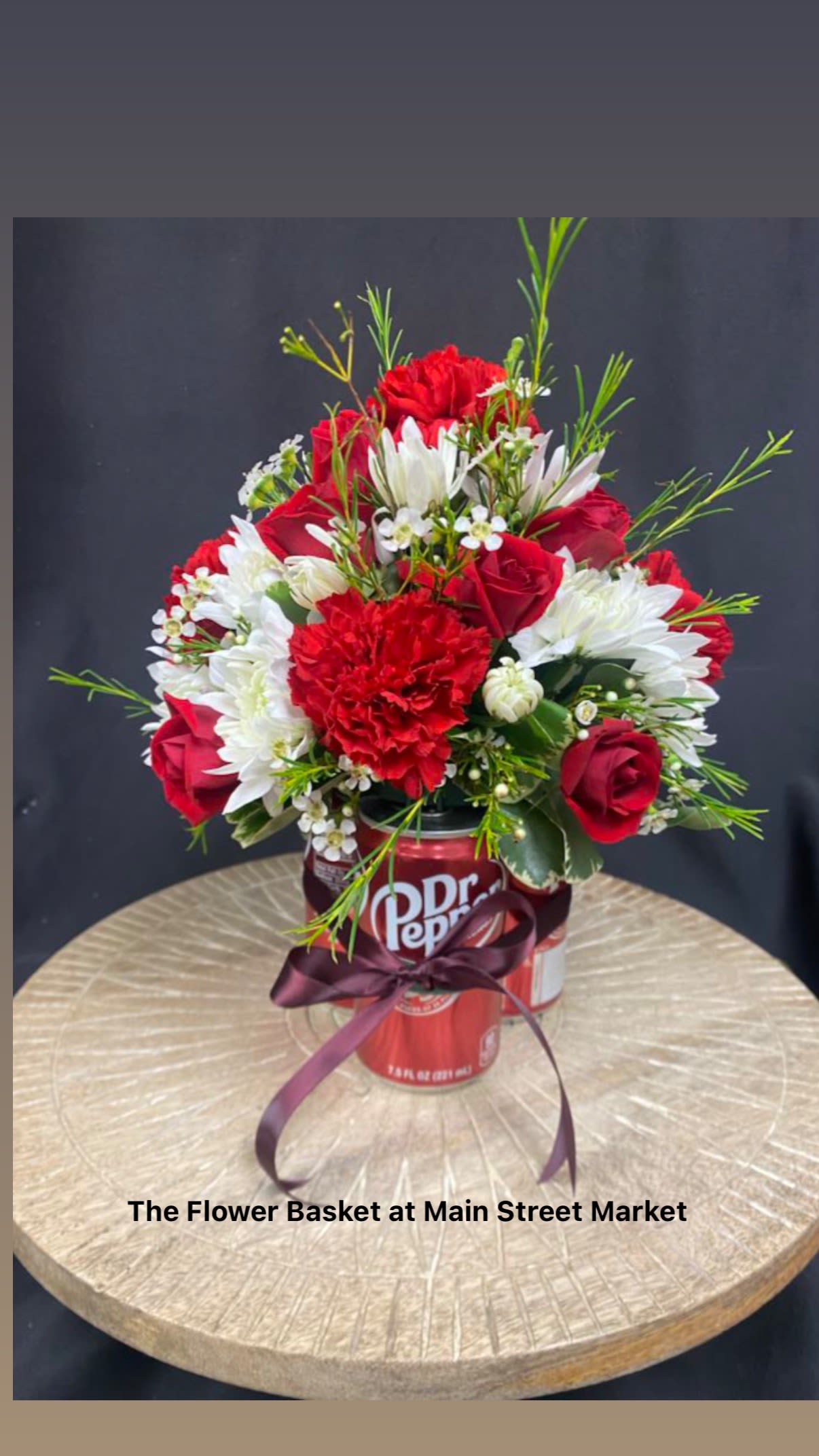 Red and white flower arrangement in a Dr Pepper can with a ribbon