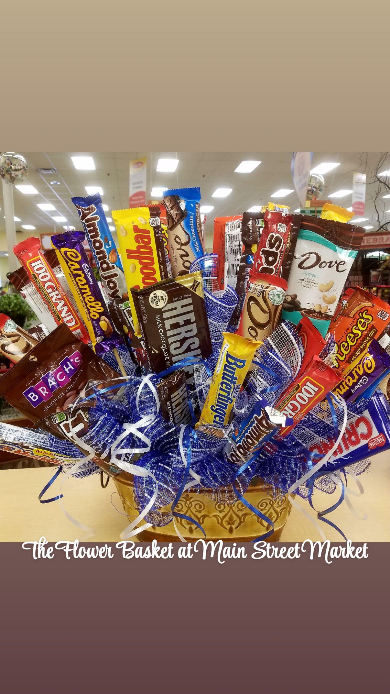 Basket arrangement of assorted candy bars with blue ribbon