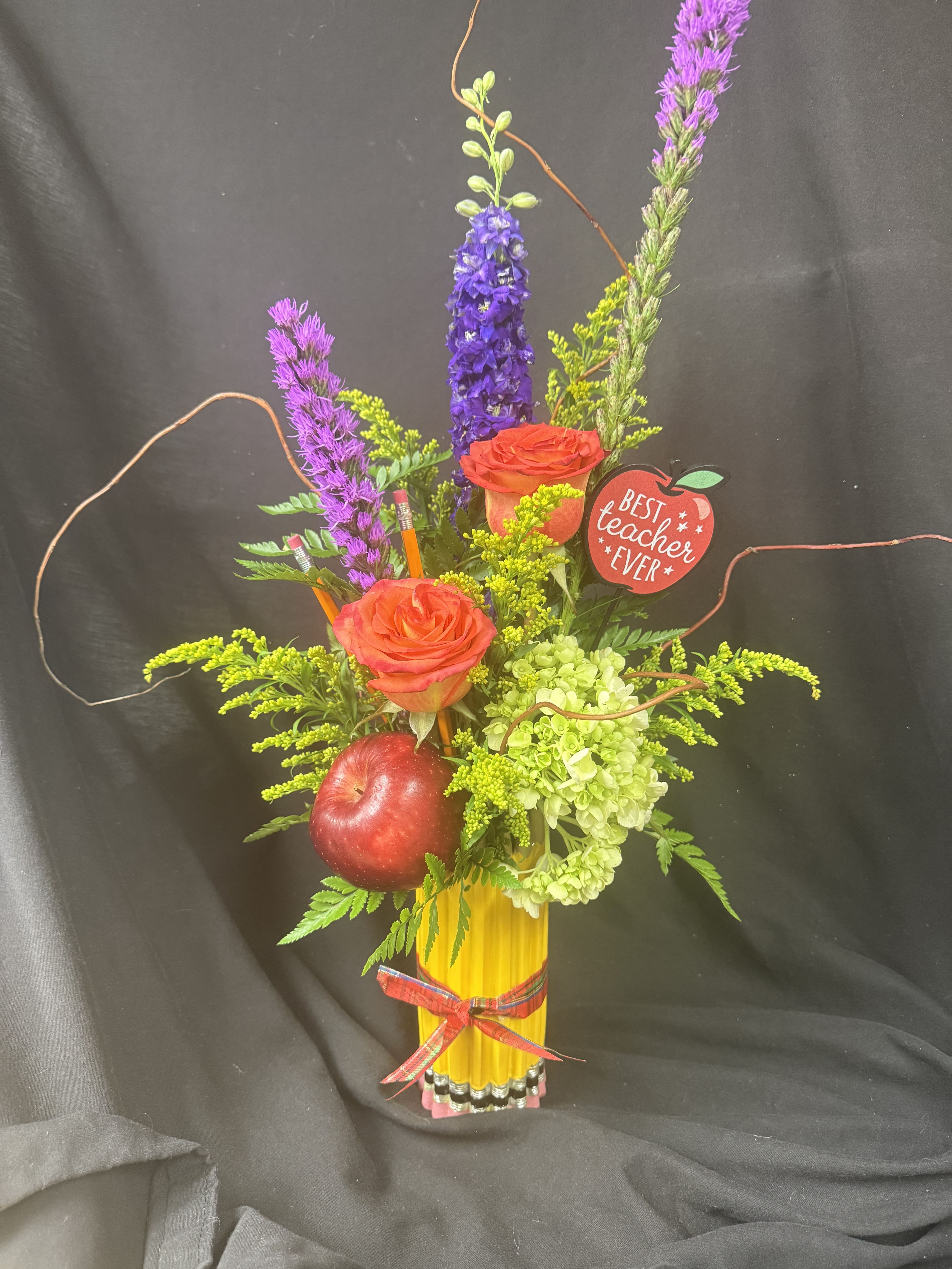 Mixed floral arrangement with roses, hydrangea, and an apple in a yellow vase