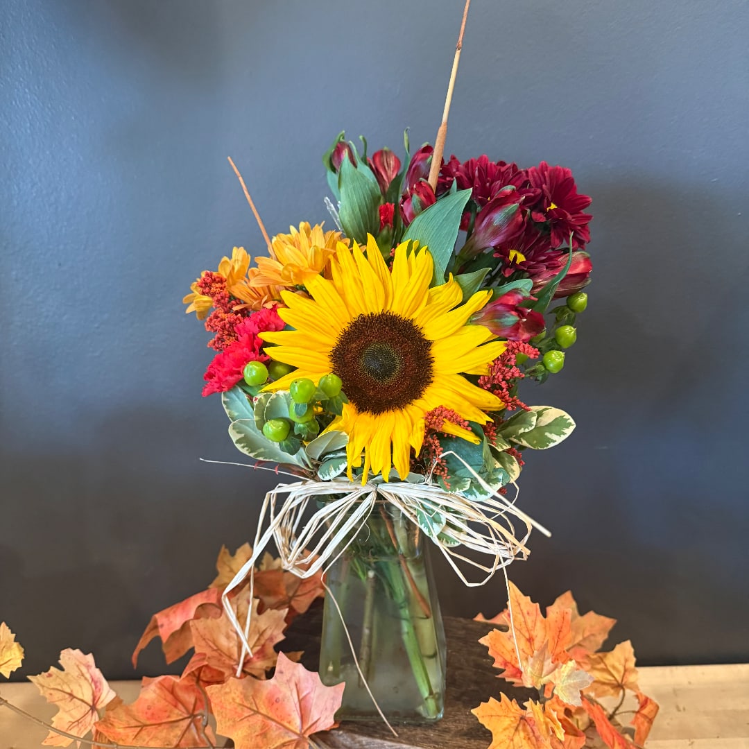 Sunflower bouquet in a glass vase with orange and burgundy flowers