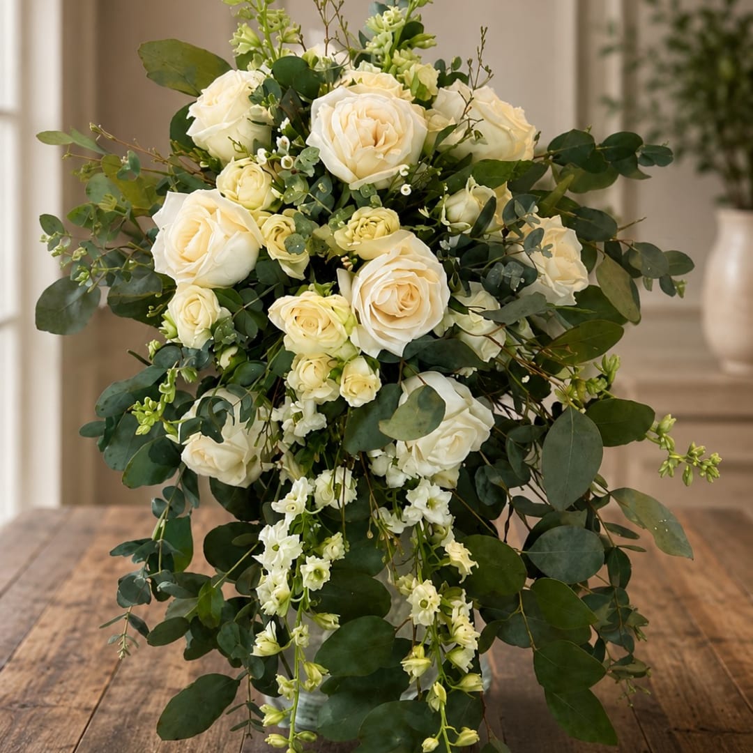 Cream rose bouquet with cascading greenery on a wooden table