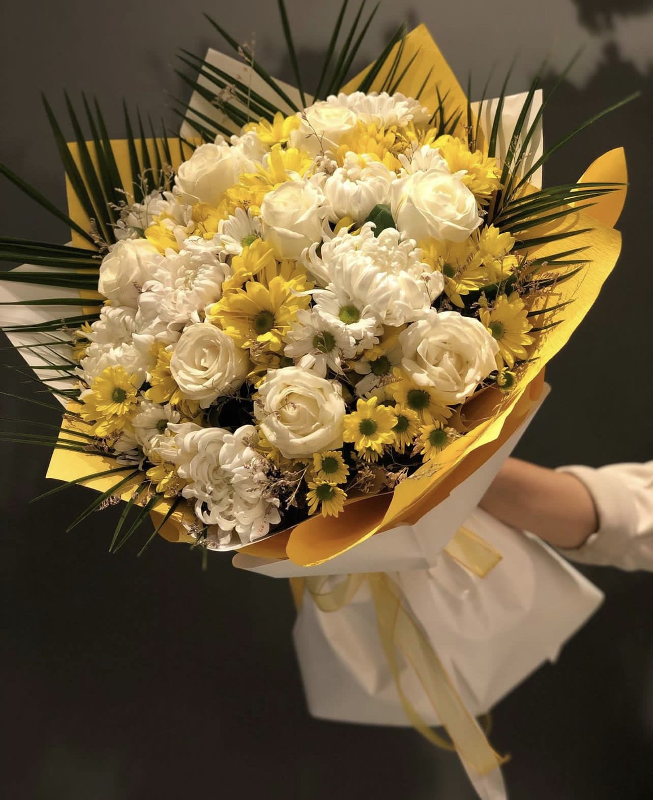 Bouquet of white and yellow flowers wrapped in white and yellow paper