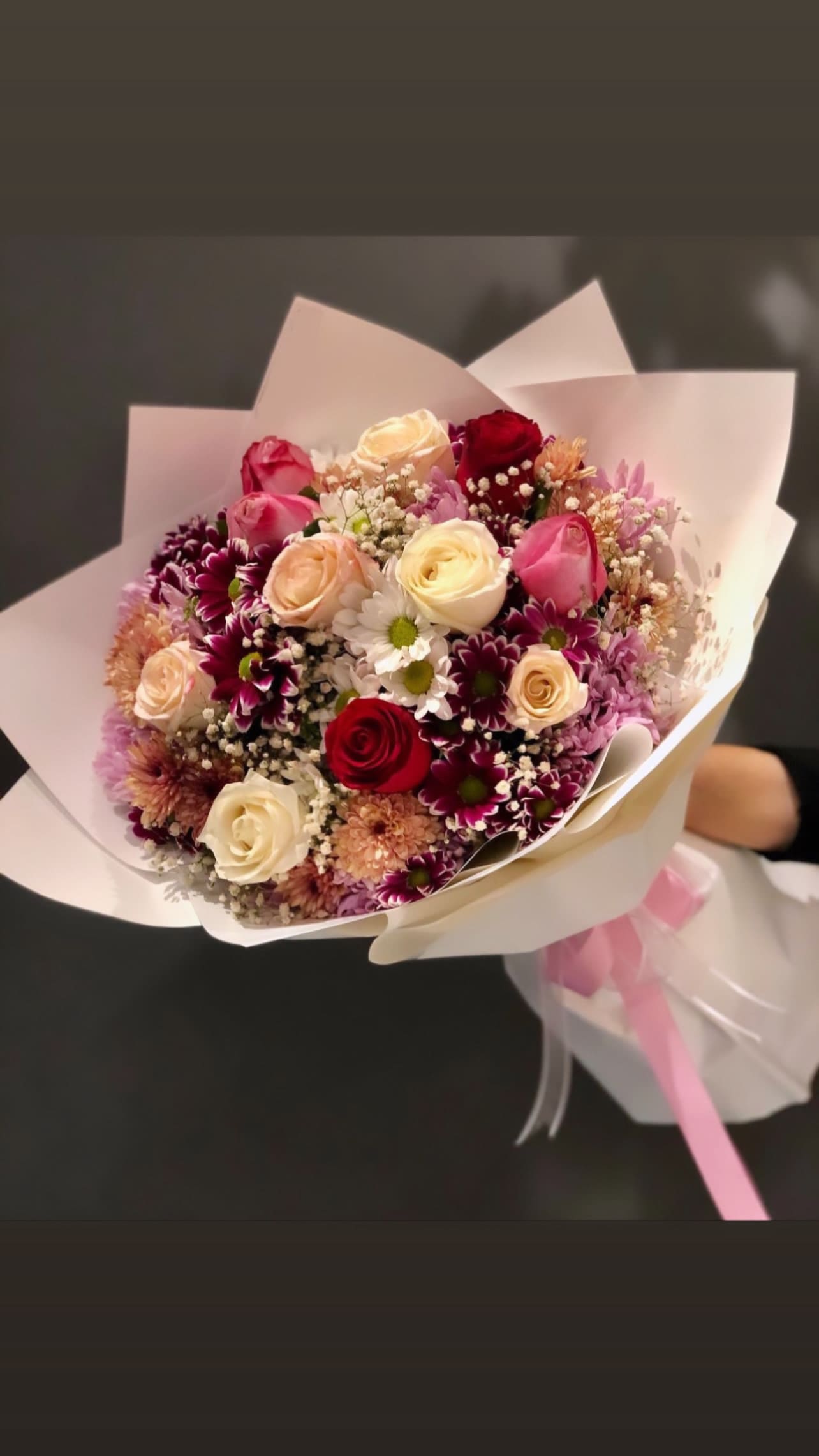 Mixed bouquet of roses and daisies wrapped in white paper