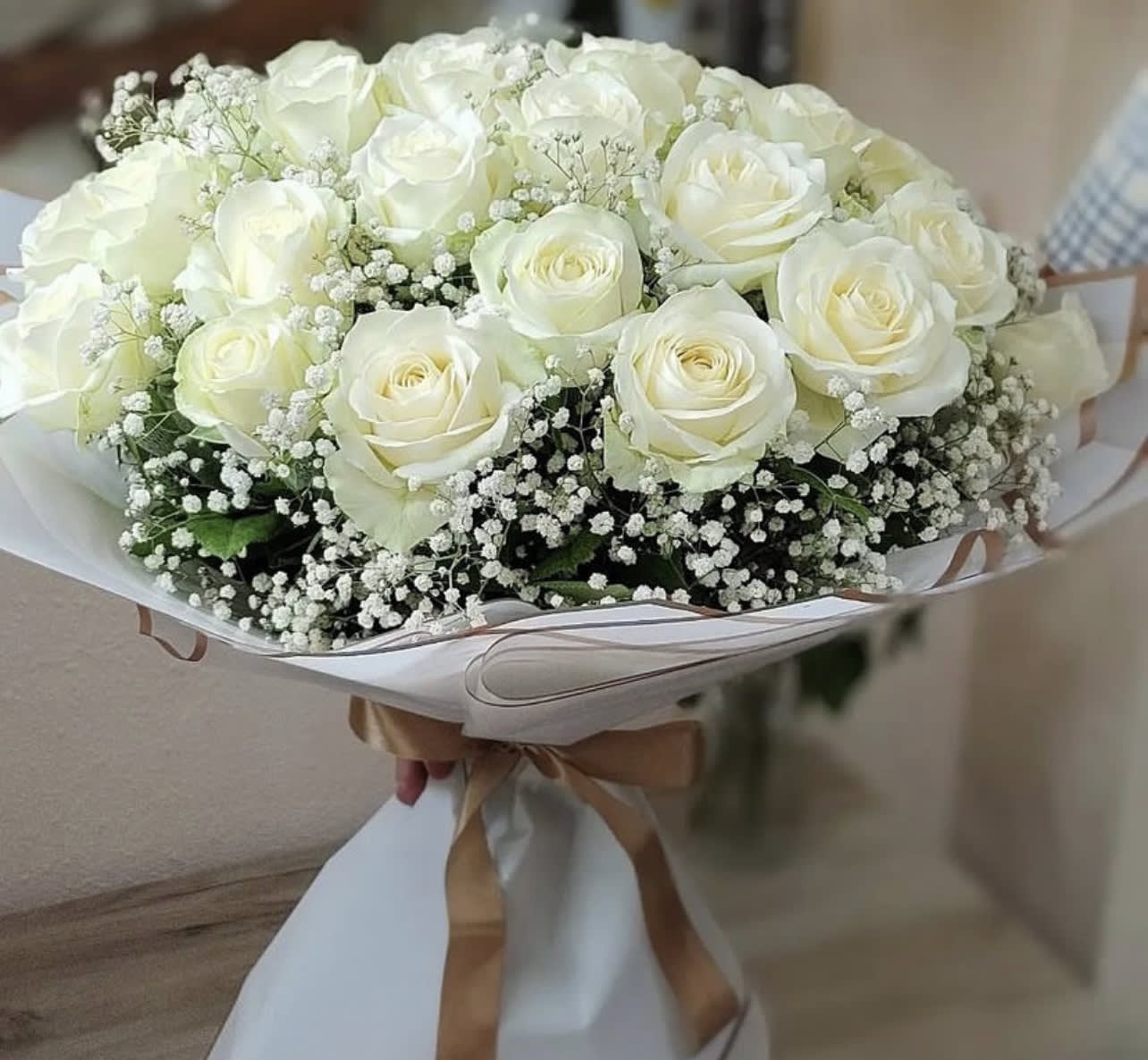 Bouquet of white roses with baby's breath wrapped in white paper