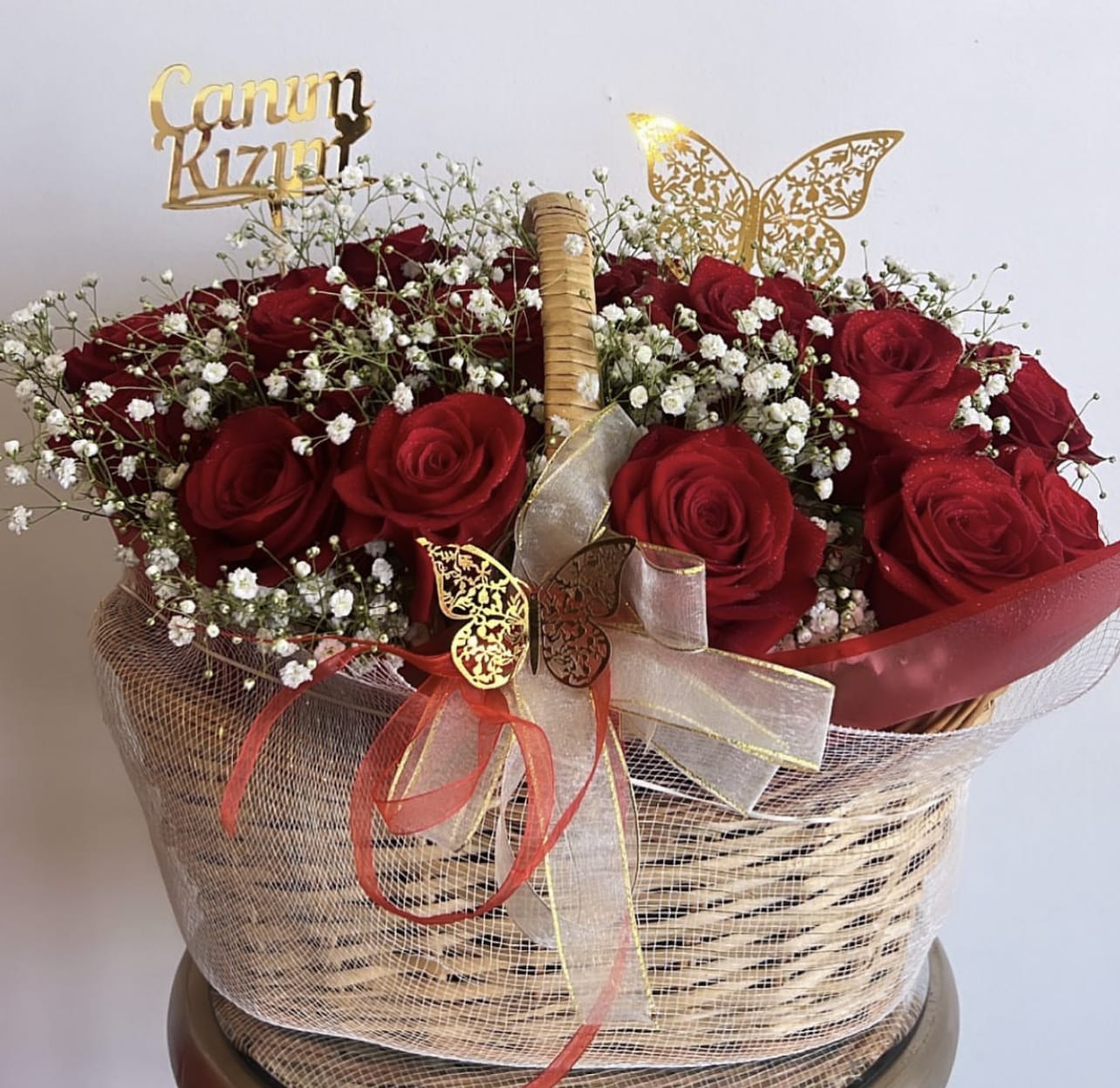 Basket of red roses with baby's breath and decorative ribbons