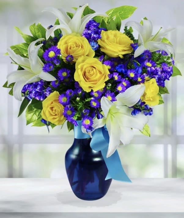 Yellow roses and purple daisies in a blue vase with white lilies