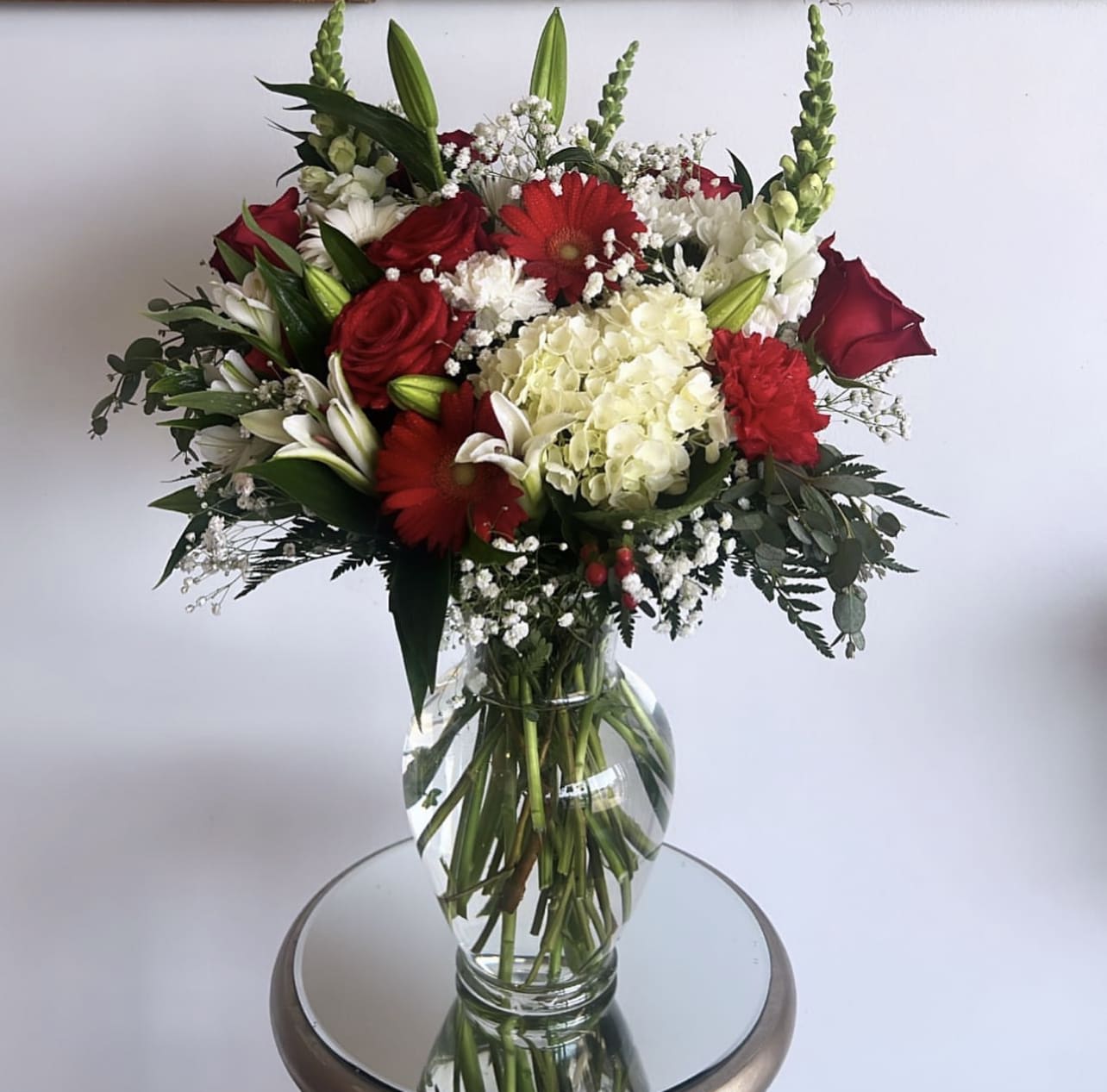 Red and white mixed flower bouquet in a clear glass vase