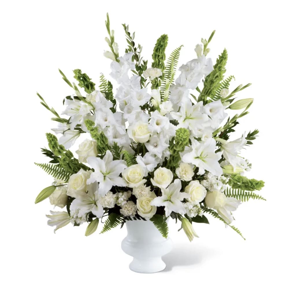White floral arrangement in a white vase with lilies and roses