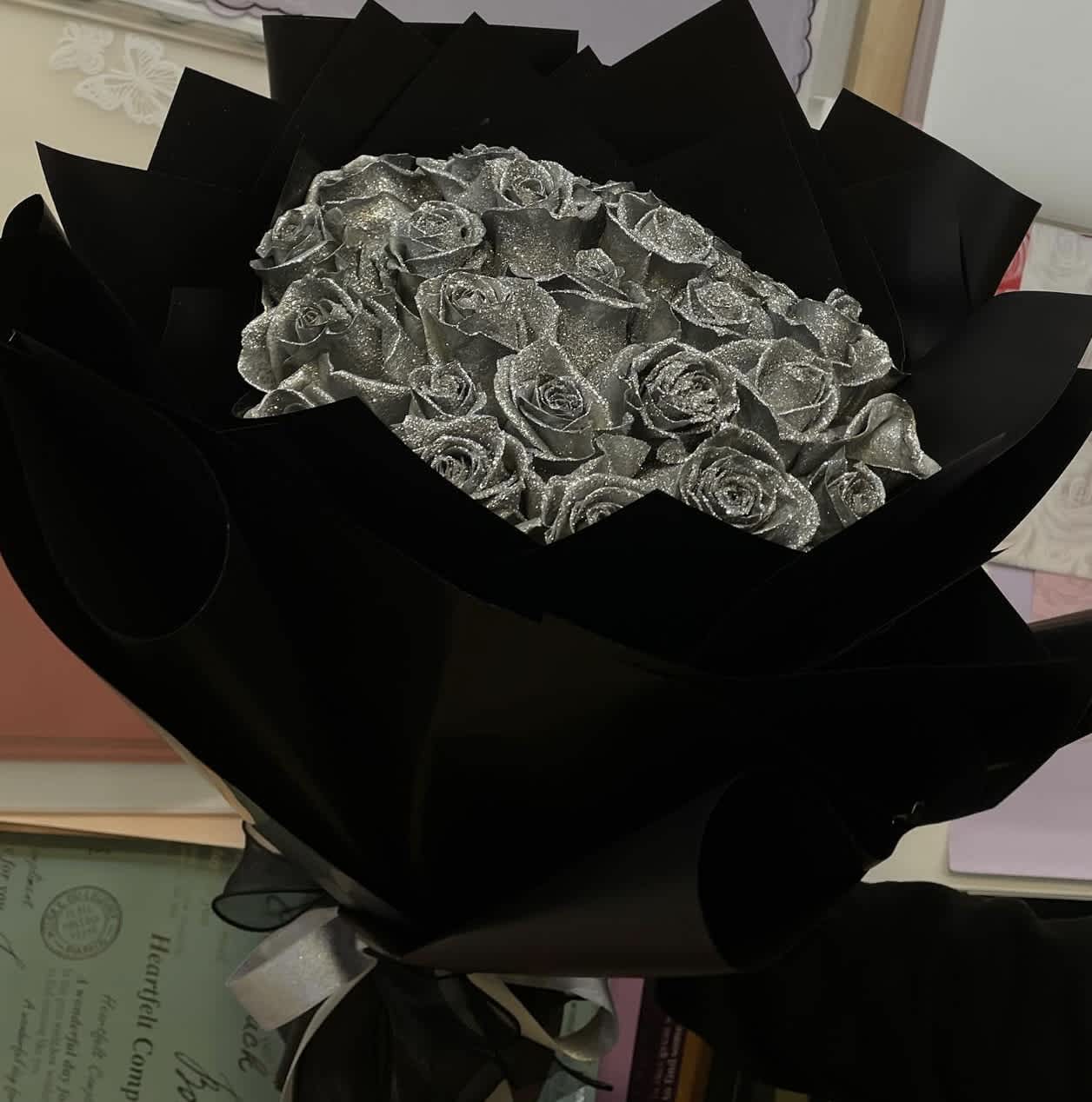 SILVER ROSE BOUQUET - Introducing the epitome of elegance and grace, behold the exquisite 25 Silver Roses. Crafted with utmost precision and adorned with shimmering silver petals, these resplendent blooms are a testament to timeless beauty. Each delicate rose is meticulously handcrafted, ensuring a unique and captivating masterpiece. The lustrous silver finish adds a touch of opulence, making these roses a perfect addition to any luxurious setting. Whether displayed as a centerpiece or gifted to a loved one, the Silver Roses are a symbol of sophistication and everlasting love. 