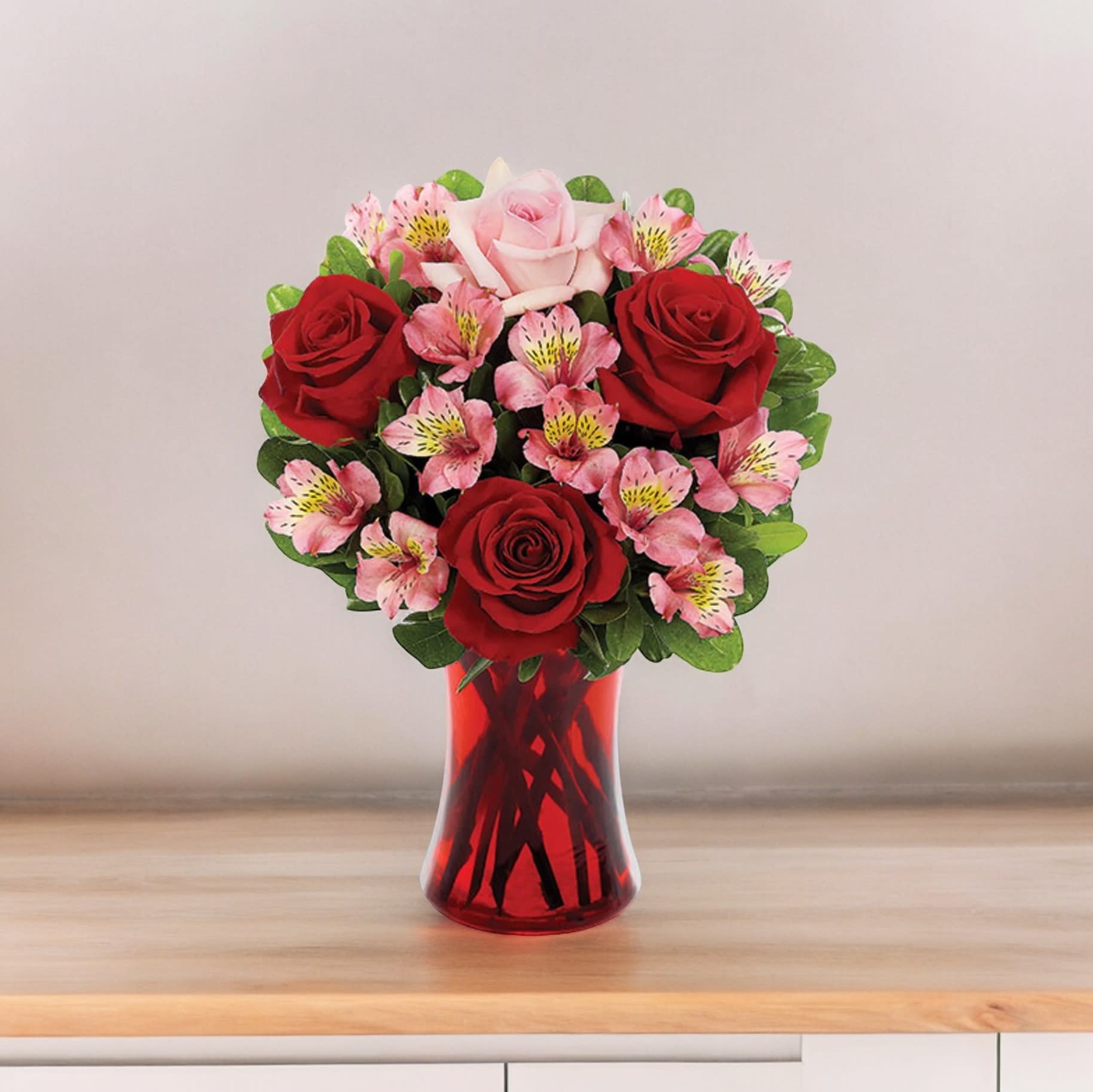 Bouquet of red and pink roses in a red glass vase