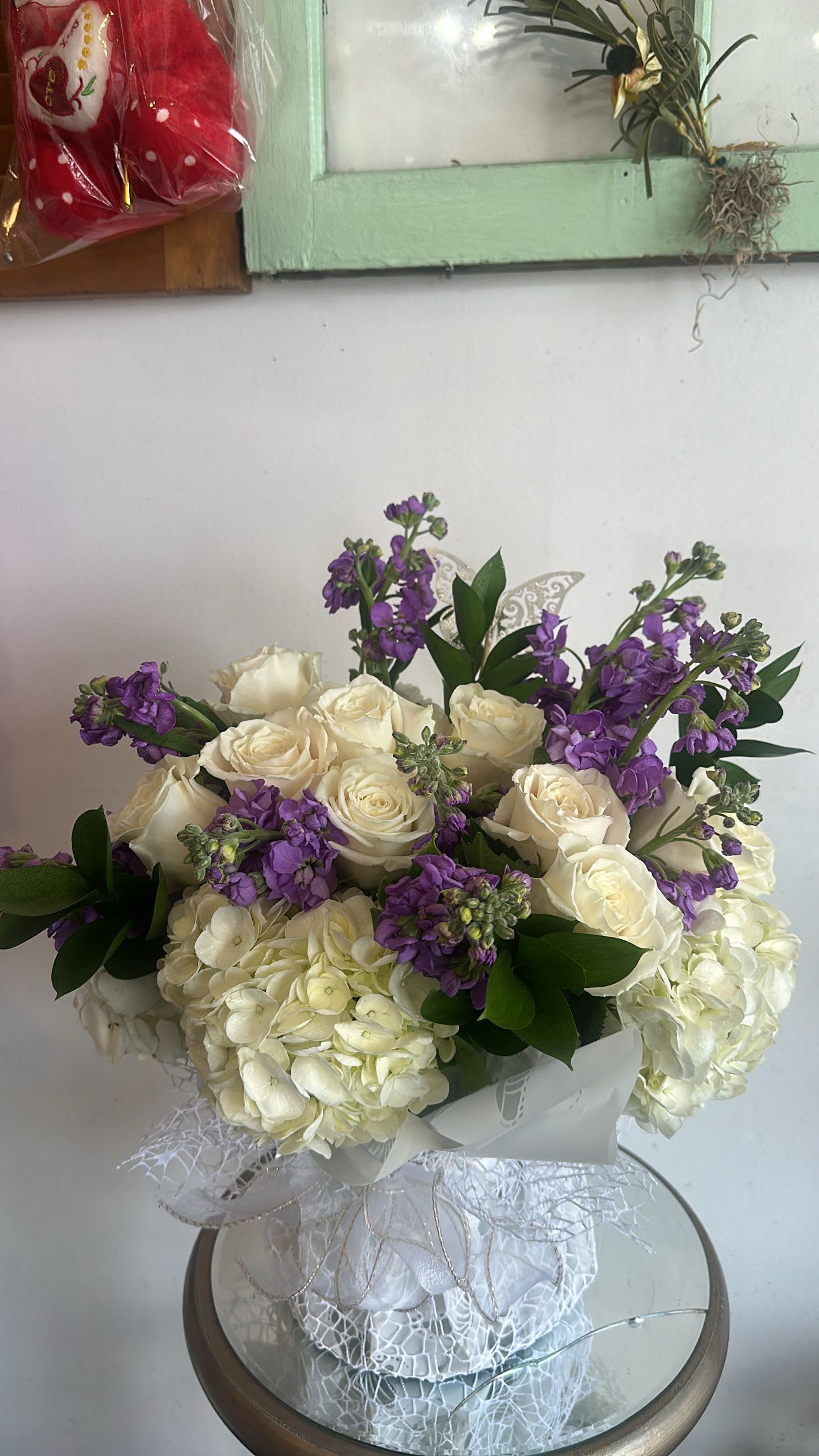 White roses and purple flowers arranged in a wrapped bouquet